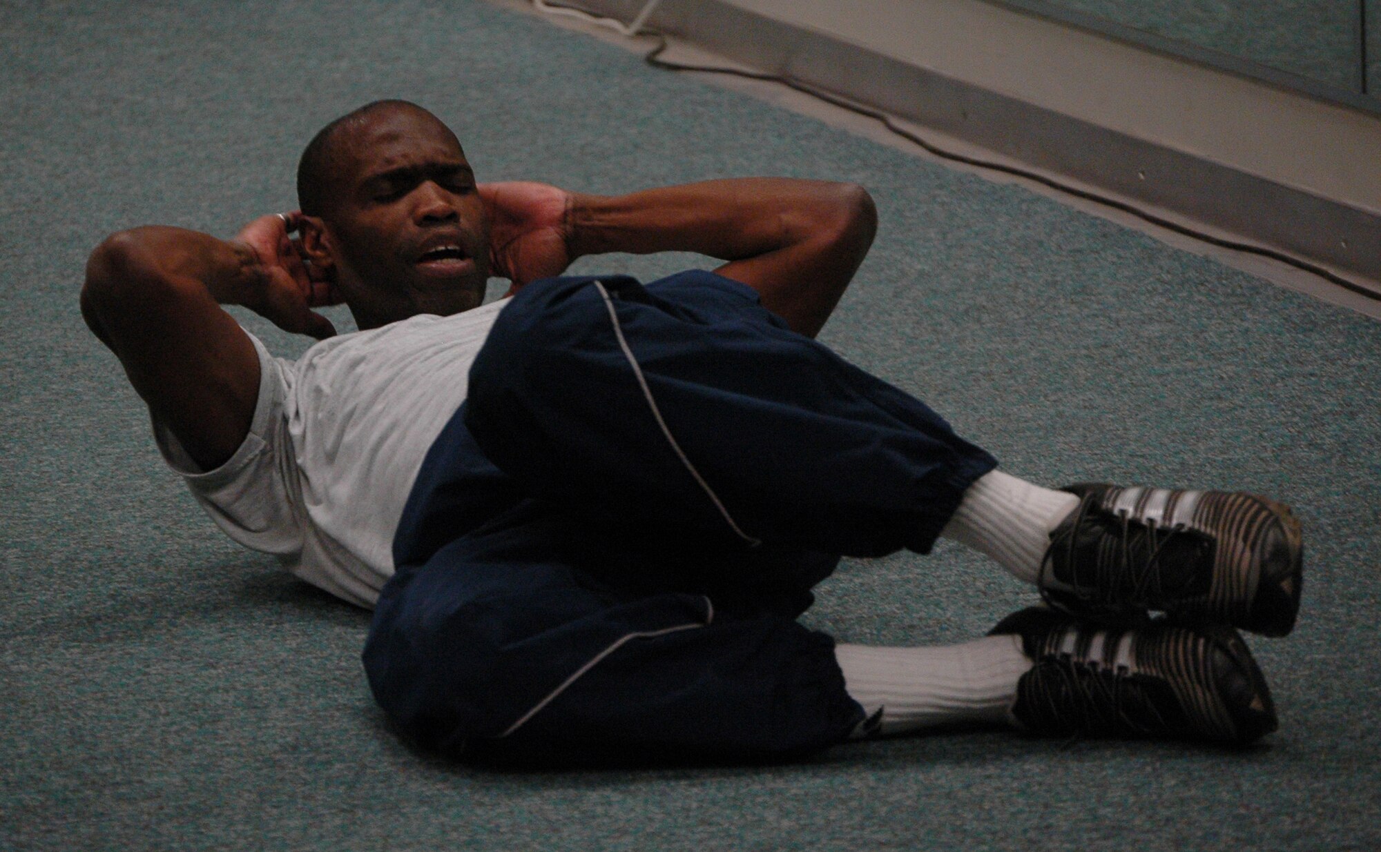 Master Sgt. Kwame Tawiah, a 512th Logistics Readiness Flight logistics planner, shows members of the 512th LRF how to perform a side crunch April 10 at the Fitness Center here. The commander mandated physical fitness session was tailored to improve members? push-up, sit-up and run scores in preparation for the new Air Force physical test.  (U.S. Air Force photo/Staff Sgt. James Bolinger) 