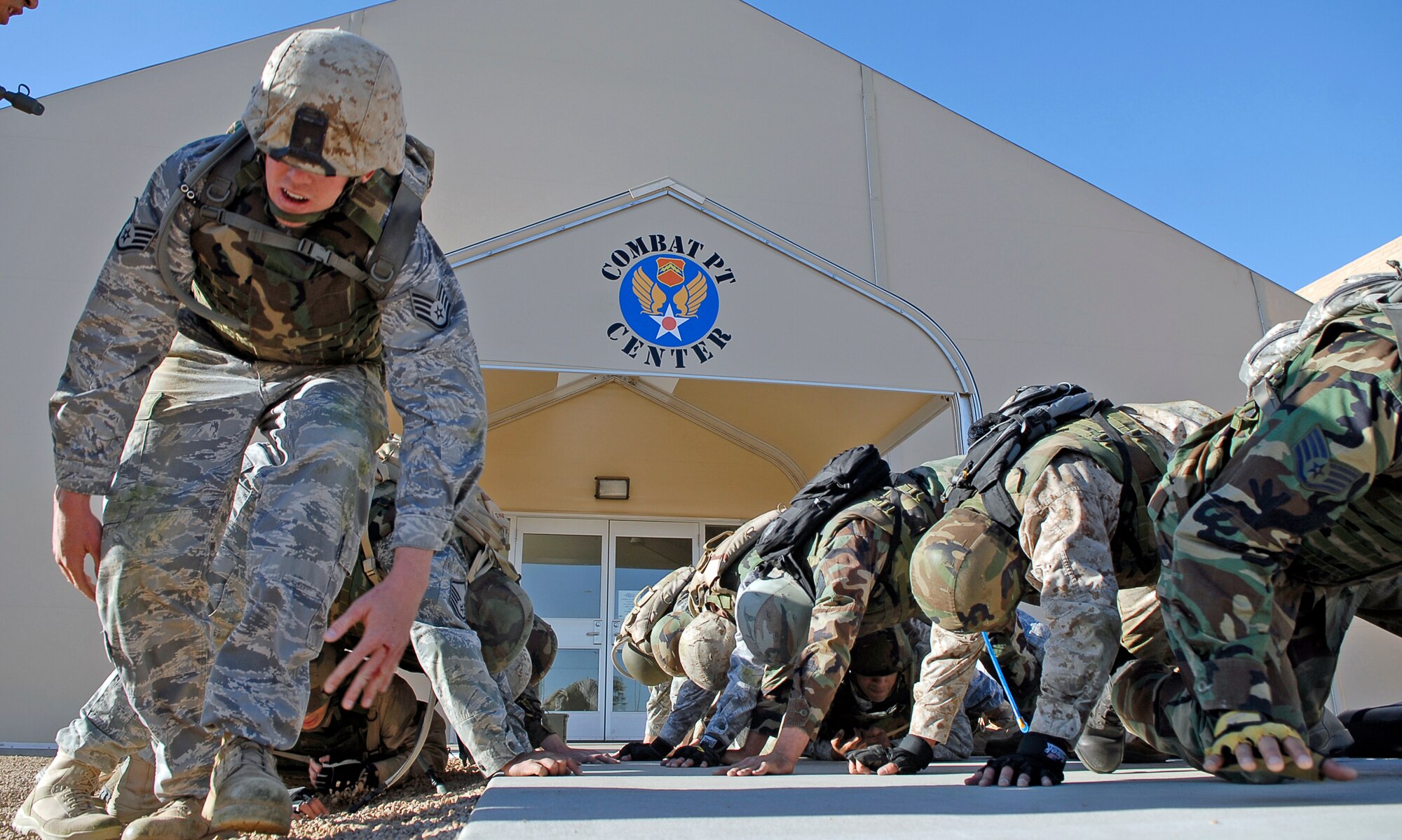 Staff Sgt. Ryan Cobb (left) positions himself to continue "building a house," April 7, 2010, at Luke Air Force Base, Ariz. During this event, squad members construct a human-made tunnel allowing team members to crawl underneath one another as conditioning for a military combative training course. (U.S. Air Force photo/Airman 1st Class Ronifel Yasay)
