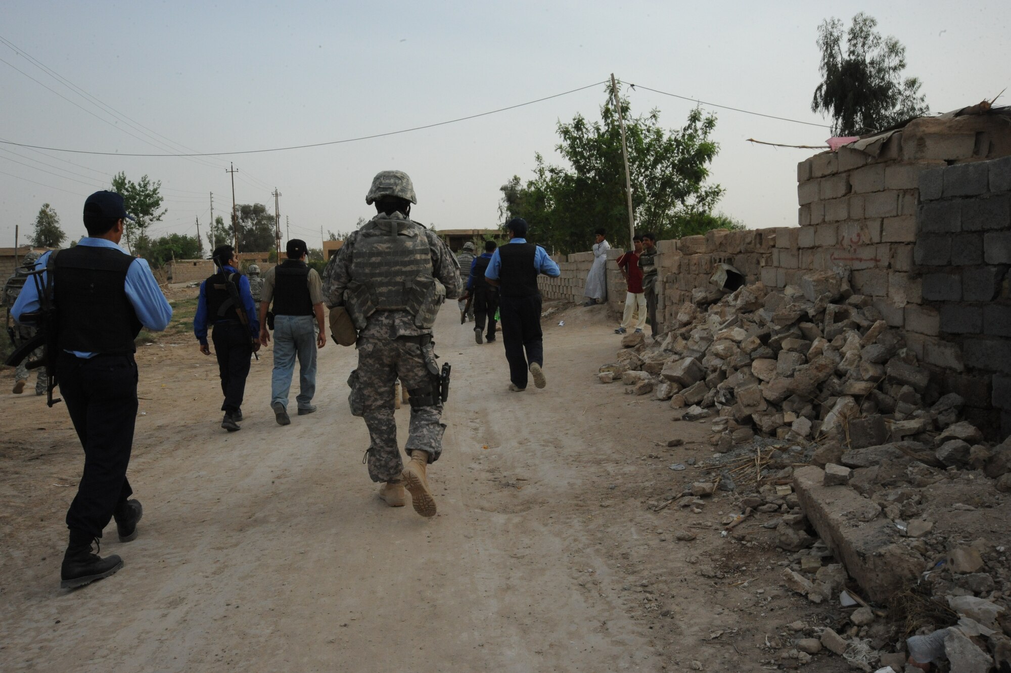 Iraqi families come outside to greet and watch members of the Iraqi Police and the 732nd Expeditionary Security Forces Squadron, Detachment 2, walk through their streets during a joint presence patrol near Rufush, Iraq, April 4, 2010.  The 732nd Expeditionary Security Forces, Detachment 2, conducted a “training and mentoring” mission, which was requested by the local police. During this mission, Air Force personnel trained the police in community policing and assisted with patrolling through a village recently overwhelmed by terrorist attacks.  (U.S. Air Force photo/Master Sgt. Trish Bunting/ Released)