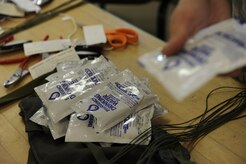 Airmen with the 437th Operations Support Squadron float section pack emergency water packets into ML-4 kits April, 7, 2010, on Joint Base Charleston, S.C. The ML-4 kits are attached to parachutes for aircrew members in the event they egress the aircraft. The kit contains a life raft and required survival equipment for over-land or over-water survival situations. (U.S. Air Force photo/Senior Airman Jennifer Flores)