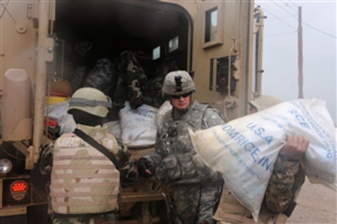 A U.S. Army soldier from Alpha Company, 1st Battalion, 30th Infantry Regiment, 2nd Brigade Combat Team, 3rd Infantry Division hands bags of supplies to members of the Combined Security Force to give to local villagers in Hassad, Iraq, on March 28, 2010.  The Golden Lions of the Combined Security Force delivered bags of supplies and toys for children in two villages to demonstrate good will and maintain a positive relationship with local citizens.  