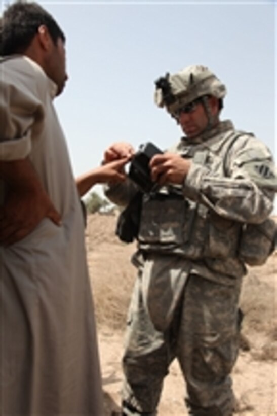 U.S. Army Spc. Patrick McDougall, of 2nd Squadron, Bravo Company, 7th Cavalry Regiment, uses a Hand-held Interagency Identity Detection Equipment System to record information on a local Iraqi man near Mahmudiyah, Iraq, on Apr. 3, 2010.  