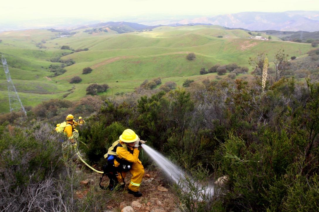 Firefighters with Camp Pendleton’s Fire and Emergency Services simulate extinguishing a fire during the department’s first Multi-company Hoselay and Rule of Engagement Drill at Camp Pendleton, April 14. More than 130 firefighters from the base’s 11 fire stations participated in the special exercise, April 14 - 16. The drill took firefighters through pseudo wildfire scenarios that forced them to negotiate steep and virtually inaccessible terrain, in preparation for the fast approaching fire season.