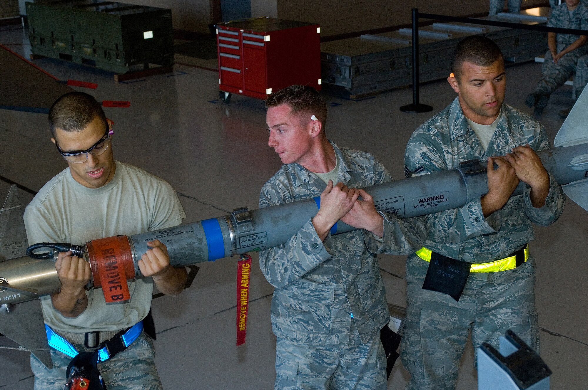 (left to right) Airman 1st Class Taylor Quintero, Staff Sgt Josh Armstrong, and Senior Airman Brian McGovern, weapons technicians from the 56th Aircraft Maintenance Squadron, lift an AIM 9 inert missile to be loaded onto an aircraft during a Load Crew Competition at Luke Air Force Base, Ariz., April 9. (U.S. Air Force Photo by Staff Sgt. Jason Colbert)