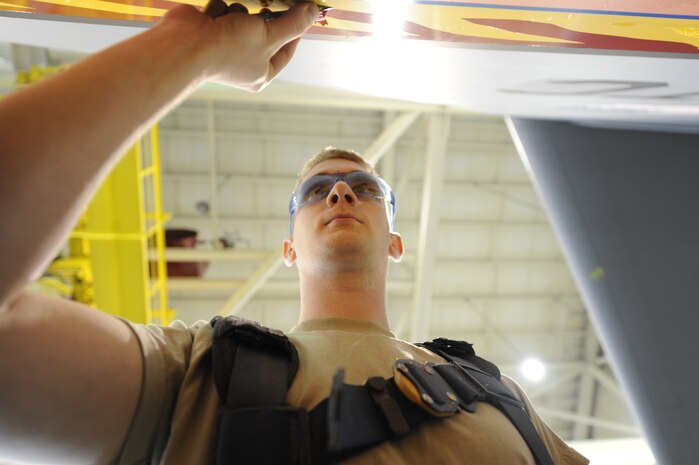 U.S. Air Force Airman 1st Class Mark Staley removes an Altus C-17 tail flash with a razor blade April 12, 2010, at Joint Base Charleston, S.C. Removing the the old tail flash vinyl is the first step on transforming the aircraft into a Charleston C-17. Airman Staley is an aircraft structural maintenance journeyman with the 437th Maintenance Squadron. (U.S. Air Force photo by James M. Bowman/released)