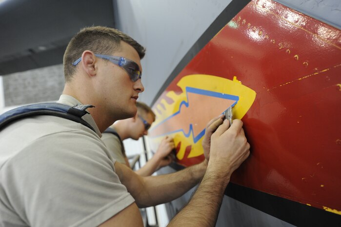 U.S. Air Force Airman 1st Class Jacob Carey and Airman 1st Class Mark Staley remove an Altus C-17 tail flash with razor blades April 12, 2010, at Joint Base Charleston, S.C. Removing the the old tail flash vinyl is the first step on transforming the aircraft  into a Charleston C-17. Both airman are aircraft structural maintenance journeyman with the 437th Maintenance Squadron. (U.S. Air Force photo by James M. Bowman/released)