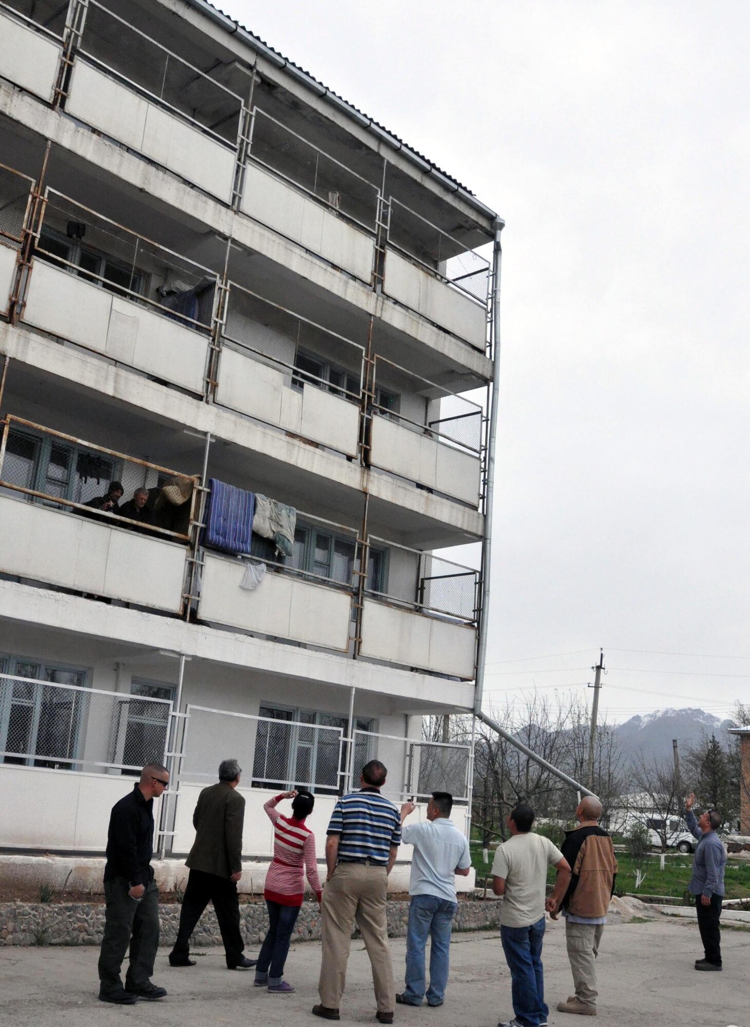 Airmen from the Transit Center at Manas, Kyrgyzstan, wave to patients on the second, third, and fourth floors of the Psychoneurologic Boarding House in Iskra Village, Kyrgyzstan, during a humanitarian assistance visit to bring food, clothing and entertainment items April 14, 2010. This boarding house hosts 255 male patients and is badly in need of repair and basic amenities. Airmen from the Transit Center at Manas visited to interact with patients and to see how they can help the boarding house in the future. (U.S. Air Force photo/Staff Sgt. Carolyn Viss)
