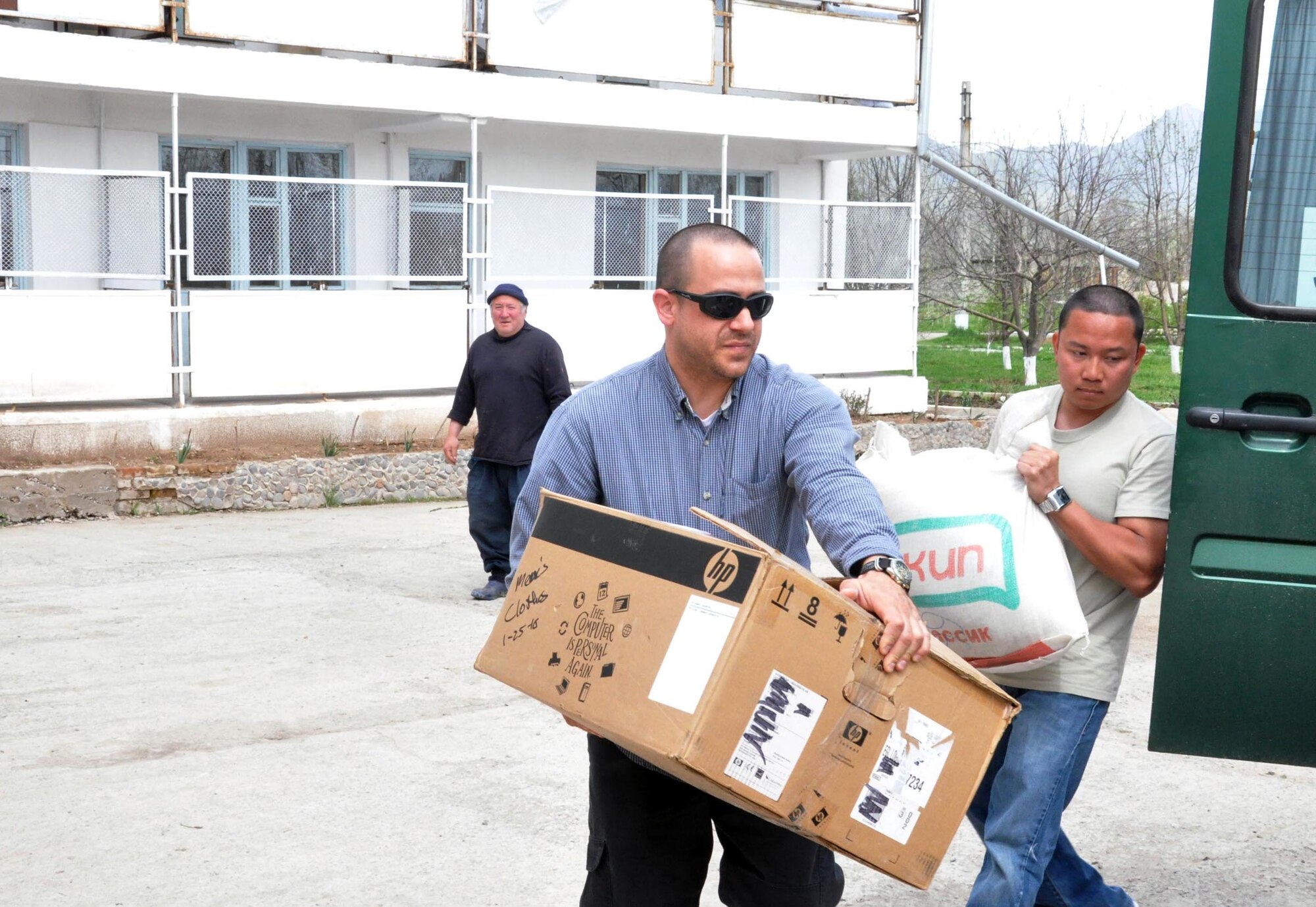 Jeff Villemarette and Staff Sgt. Jeff Legaspi (right) carry food, clothing and entertainment items for the residents of the TokMok Psychoneurologic Boarding House April 14, 2010, in Iskra Village, Kyrgyzstan. This boarding house hosts 255 male patients and is badly in need of repair and basic amenities. Airmen from the Transit Center at Manas visited to bring some humanitarian assistance items and to see how they can help the boarding house in the future. (U.S. Air Force photo/Staff Sgt. Carolyn Viss) 