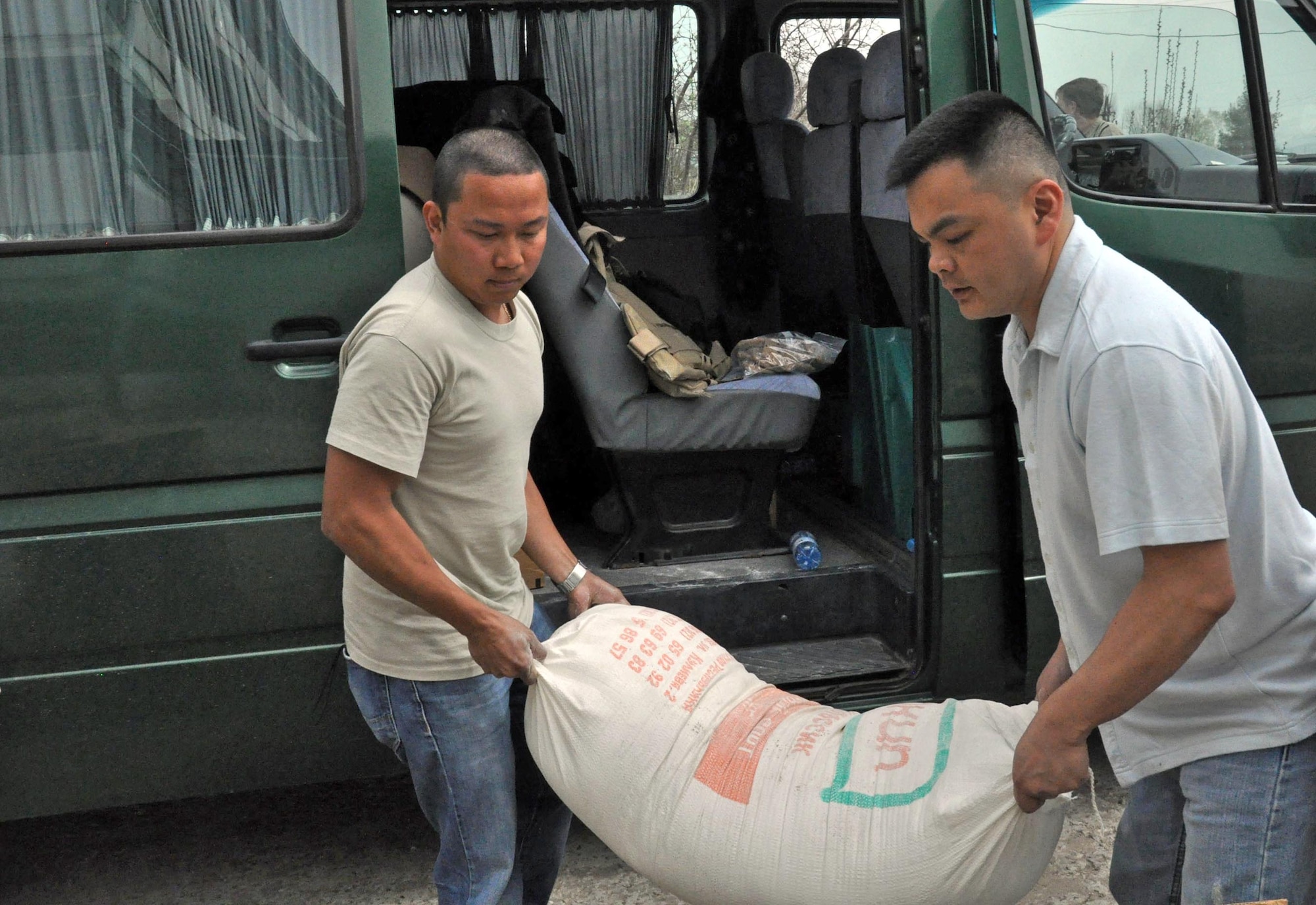 Staff Sgt. Jeff Legaspi and Capt. Tom Mulka carry a 100-pound bag of flour for the residents of the TokMok Psychoneurologic Boarding House April 14, 2010, in Iskra Village, Kyrgyzstan. Sergeant Legaspi is a 376th Expeditionary Civil Engineer Squadron electrical engineer, and Captain Mulka is the Manas Area Benefit Outreach Society president. Airmen brought food, clothing and entertainment items to patients as part of the Transit Center at Manas humanitarian outreach efforts. (U.S. Air Force photo/Staff Sgt. Carolyn Viss)
