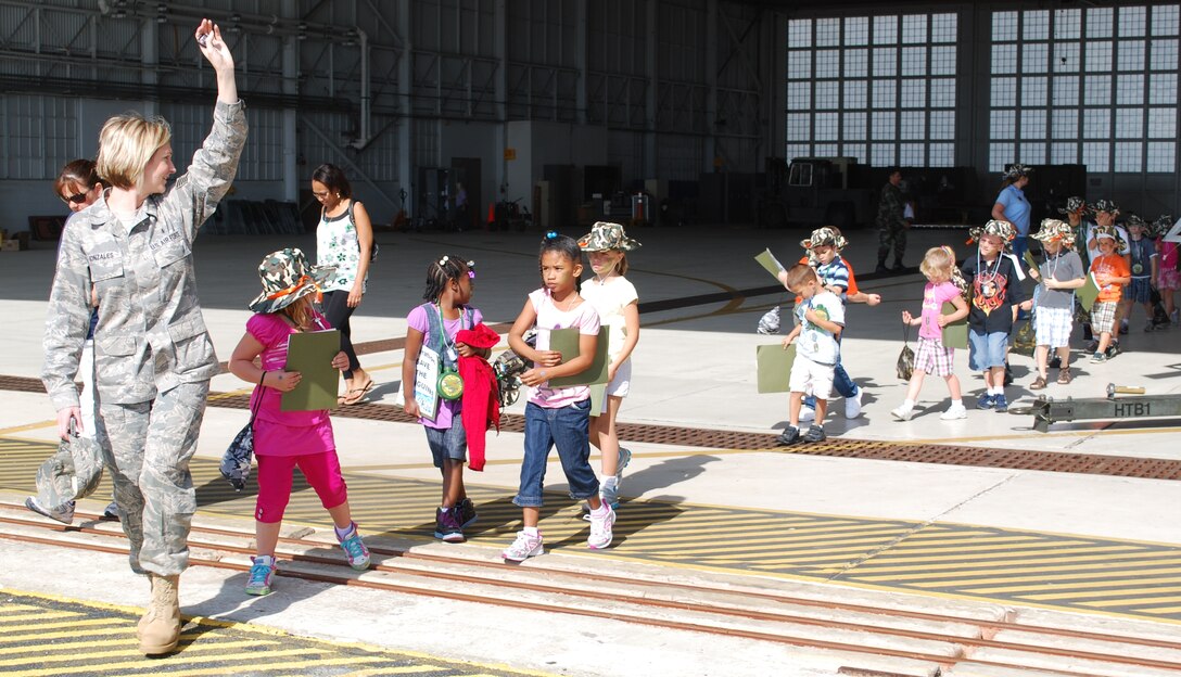 Tech. Sgt. Monica Gonzales of the Airman & Family Readiness Center acted as a troop leader for the Kids Understanding Deployment Operations event April 10. Here she leads the junior deployers out of a hangar, where they toured a HH-60 Pave Hawk
helicopter. The KUDOS program is part of the Year of the Air Force Family and helps children learn about deployments. (U.S. Air Force photo/Senior Airman David Dobrydney)