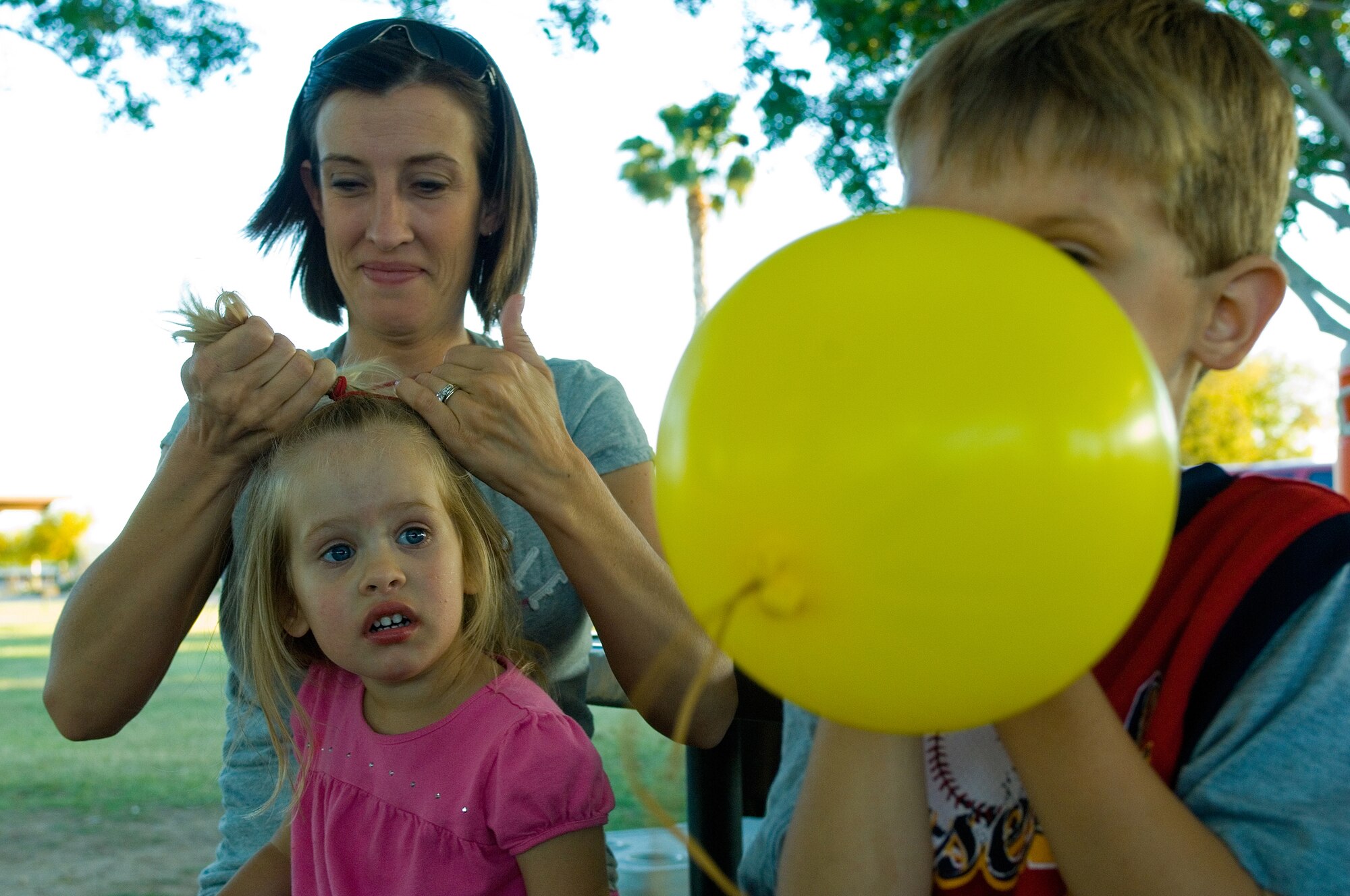 Keira King, 3, watches her brother Kaleb, 6, blow up a balloon while her mother, Nikkol King, does her hair during the Family Camp Out at Luke Air Force Base, Ariz., April 9. The children also received a movie and s'mores during their stay. (U.S. Air Force Photo by Staff Sgt. Jason Colbert)