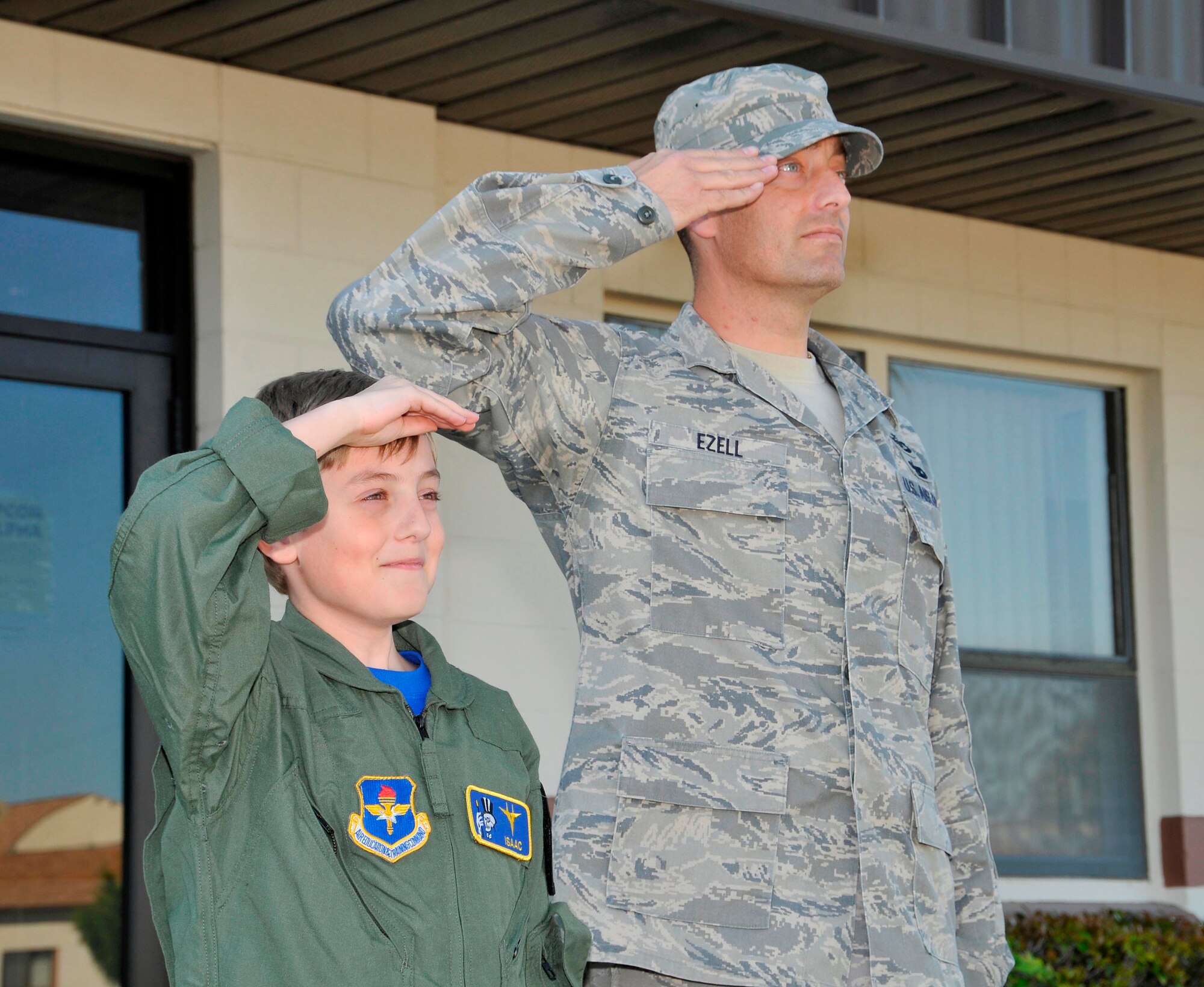 Tech. Sgt. Joe Ezell, 601st Air and Space Operations Center Operational Assessments technician, and son Isaac, salute the flag during Retreat, which signifies the end of the day. Isaac recently participated in Tyndall AFB's "Pilot for a Day" program. (U.S. Air Force Photo By: Lisa Norman)