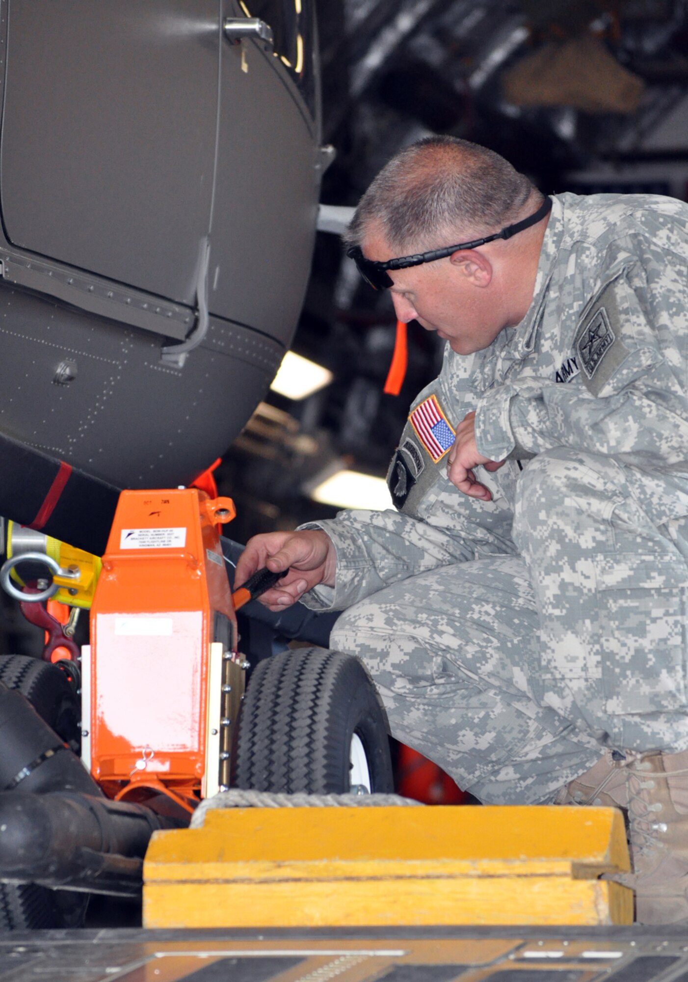 Army Chief Warrant Officer Five John Jones inspects the wheel attachment that was used to move a UH-72 Lakota into the hold of a C-17 April 12. Chief Jones is the acceptance pilot for the Army Light Utility Helicopter Program. (U.S. Air Force photo/Senior Airman Jacob Corbin). 