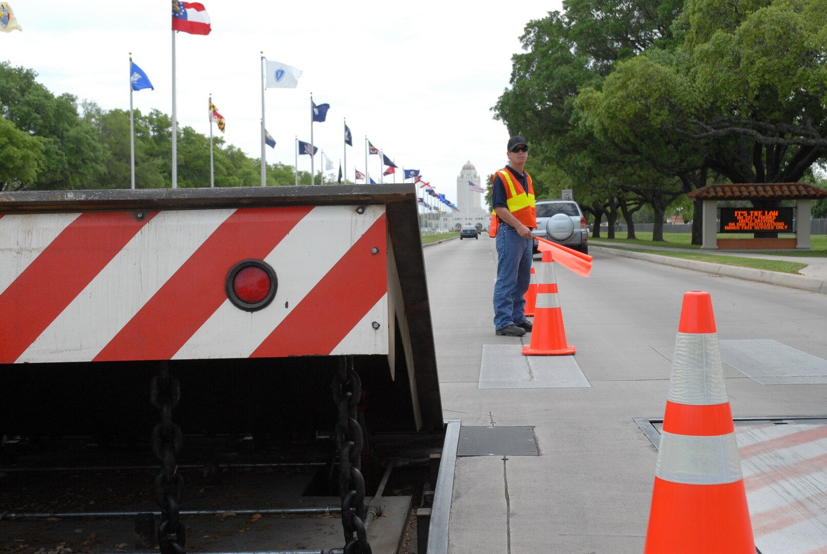 Doug Hyland, a maintenance contractor with Stobil Enterprises, directs incoming base traffic around an in-ground denial barrier on Harmon Drive at Randolph Air Froce Base, TX, April 12. (U.S. Air Force photo by Senior Airman Katie Hickerson)