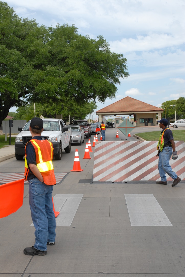 Doug Hyland, a maintenance contractor with Stobil Enterprises, directs incoming base traffic around an in-ground denial barrier on Harmon Drive at Randolph Air Froce Base, TX, April 12. (U.S. Air Force photo by Senior Airman Katie Hickerson)