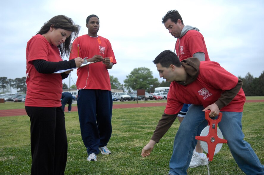 (Left to Right) Senior Airman Casey Peel, 43rd Security Forces Squadron; Airman 1st Class David Hartwell, 43rd Logistics Readiness Squadron; Edwin Byrnes, 3rd Aerial Port Squadron and Senior Airman Josh Arias, 43rd Operations Support Squadron, measures the distance of a shot put during the distance of a 2010 Mid Carolina Senior Games, April 14. The Pope Fitness Center has hosted the event for 26 years. (U.S. Air Force Photo/ 2nd Lt. Cammie Quinn)