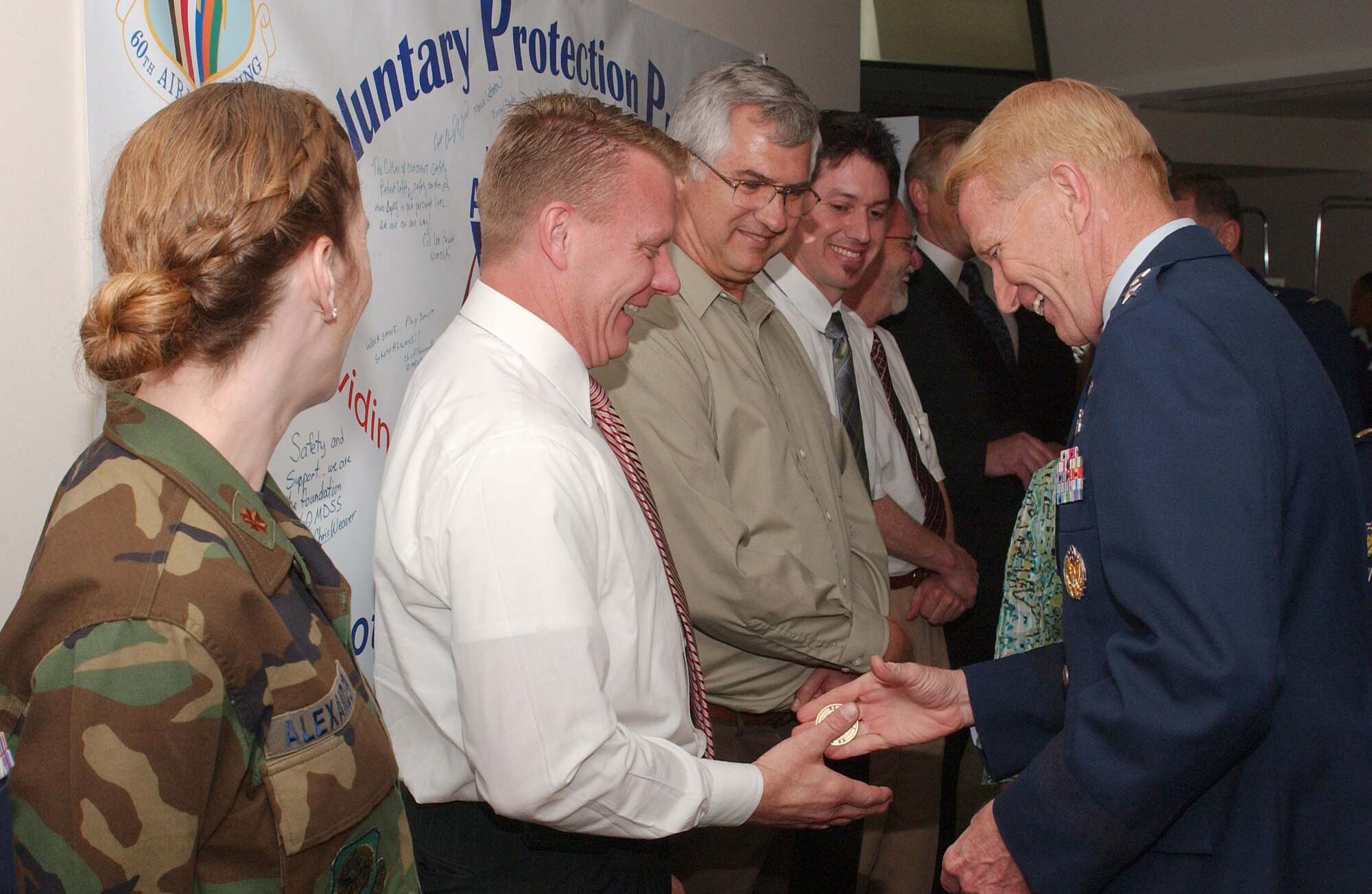 Dr. (Maj. Gen.) Thomas Loftus, assistant surgeon general for health care operations, presents Mr. Michael Culler, VPP team leader, with a coin after the VPP "STAR" ceremony April 9. (U.S. Air Force photo/ Senior Airman Liliana Moreno)        