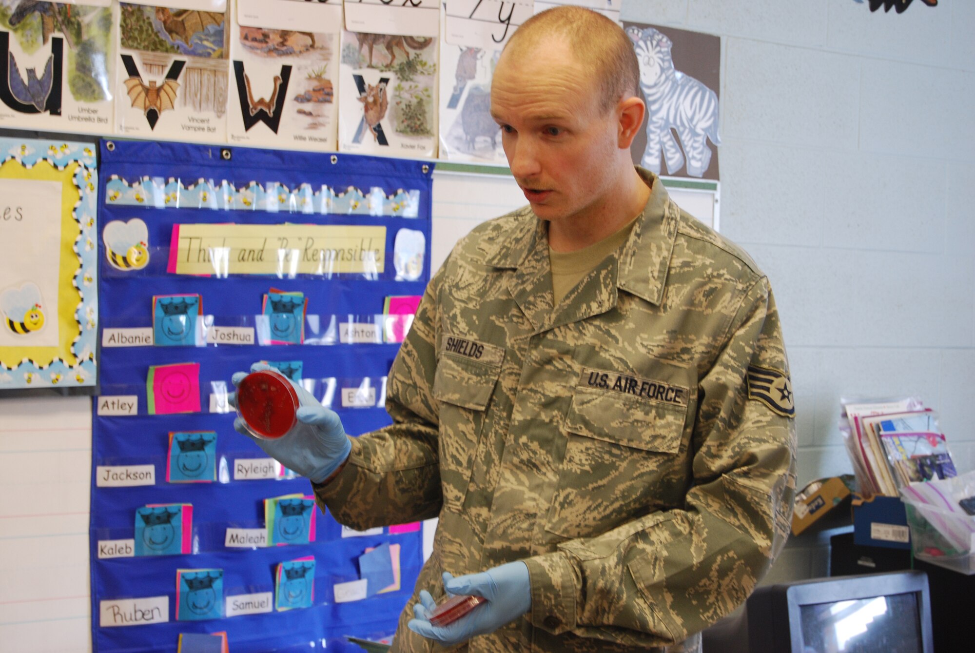 Staff Sgt. Jonathan Shields holds up a petri dish that had been incubated for 48 hours after he initially took samples from three children's hands March 31.  He came back to visit April 1 to show them the germs that were on their hands that grew. The experiment was part of a lesson on properly washing your hands. (U.S. Air Force photo/Airman 1st Class Kristina Overton)