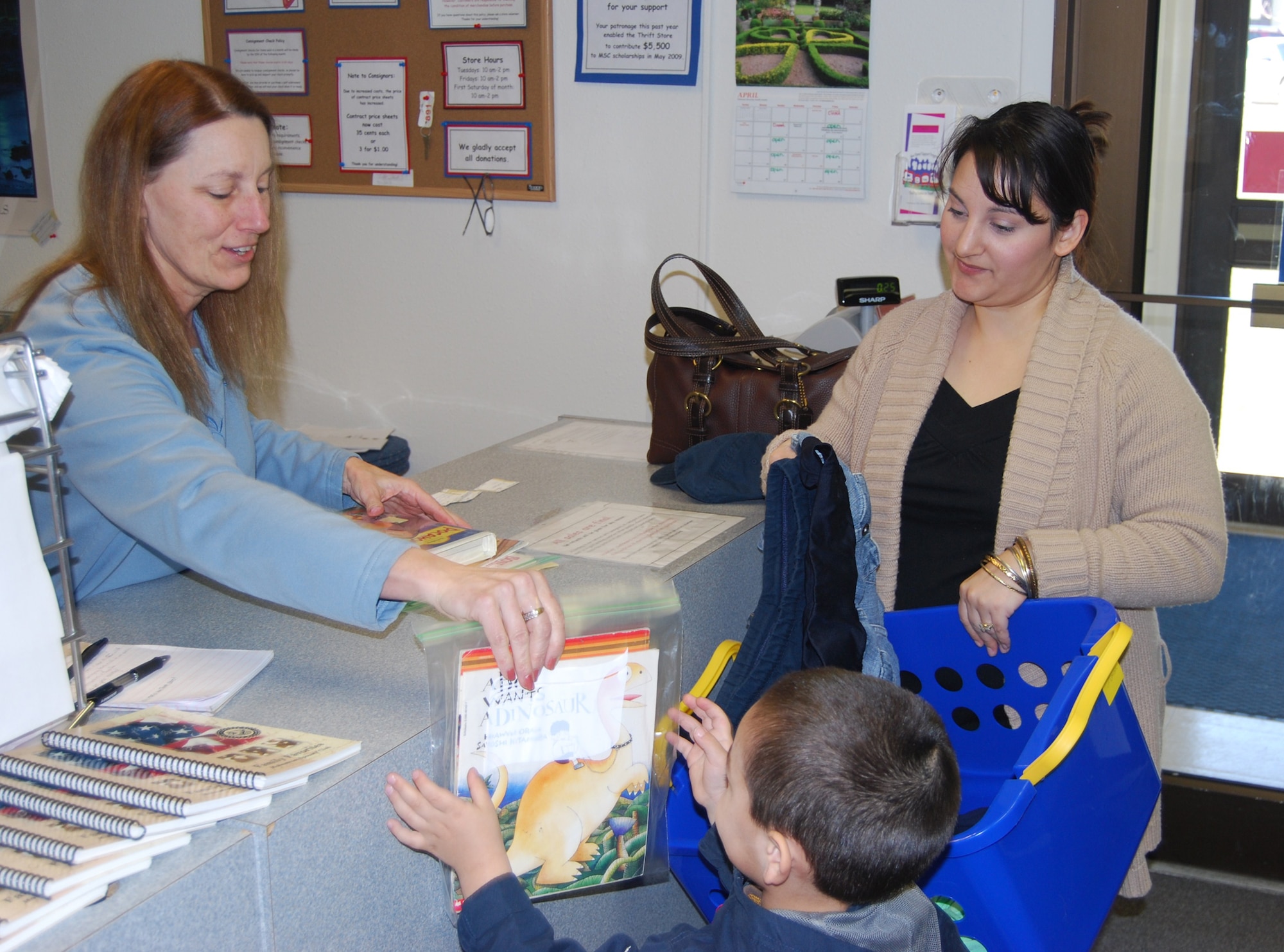 Joy Schell, Thrift Store manager, rings up some purchases at the counter for Candice Feigel and her son Joseph, 3, at the Thrift Store and Consignment Shop April 9. (U.S. Air Force photo/Airman 1st Class Kristina Overton)