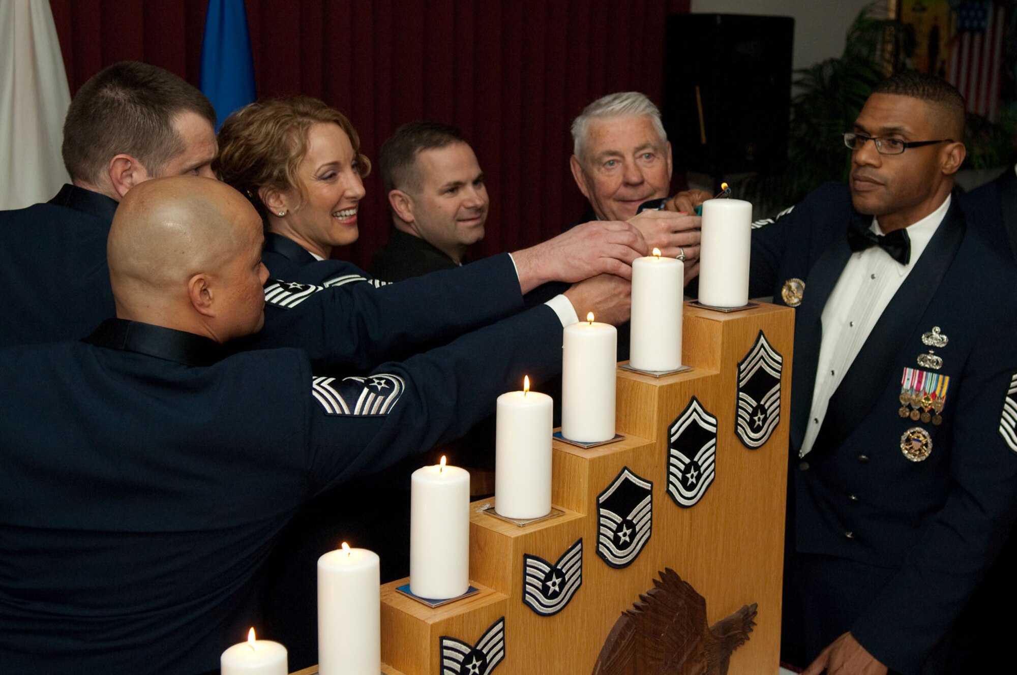 HANSCOM AIR FORCE BASE, Mass. – (l to r) Air Force Chief Master Sgt. Glenn A. Taijeron, Chief Master Sgt. Ryan Mayfield, Senior Master Sgt. Laura C. Noel and Coast Guard Master Chief Petty Officer Jeff Shumate, along with retired Chief Master Sgt. Robert D. Gaylor, fifth Chief Master Sergeant of the Air Force, and Chief Master Sgt. Kenneth A. Williams, command chief for the Electronic Systems Center and 66th Air Base Wing, light a candle representing the rank of chief master sergeant during the Chiefs Recognition Ceremony on April 9 at the Minuteman Club. (U.S. Air Force photo by Rick Berry)