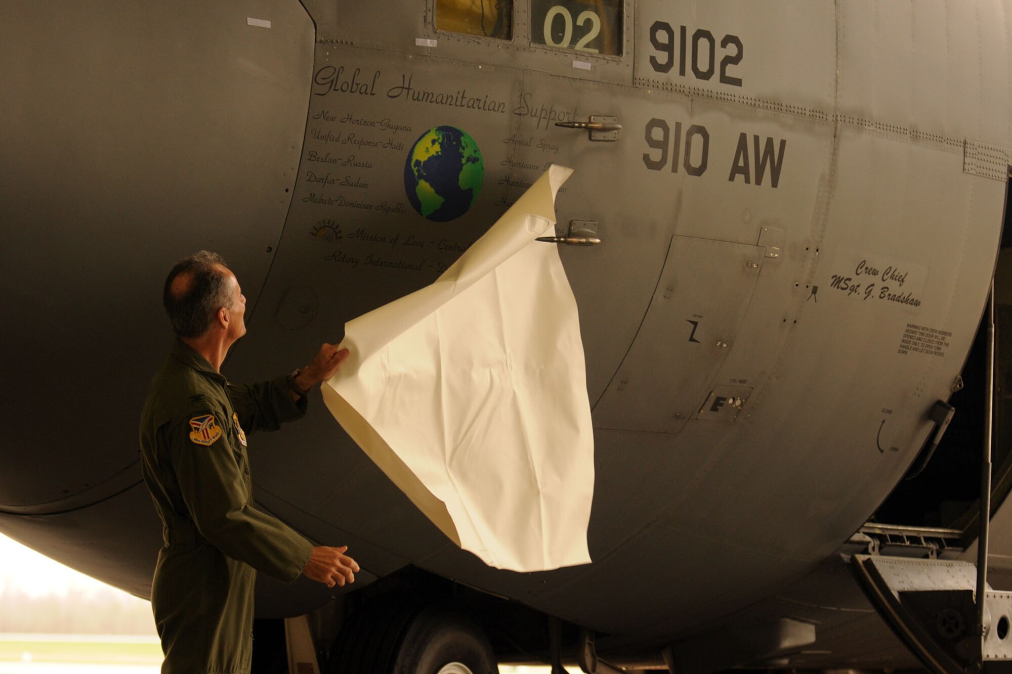 YOUNGSTOWN AIR RESERVE STATION, Ohio -- Air Force Reserve Col. Karl McGregor, commander of the 910th Airlift Wing, unveils new nose art on a C-130H Hercules tactical cargo transport aircraft during a ceremony here, April 7. The nose art titled "Global Humanitarian Support" recognizes the humanitarian missions carried out by the Citizen Airmen and aircraft of the 910th over the last several years. These missions have included aerial spray relief in the aftermatch of several hurricanes, medical services, civil engineer work and airlift support to numerous locations around the world. U.S. Air Force photo by Mr. Eric White.