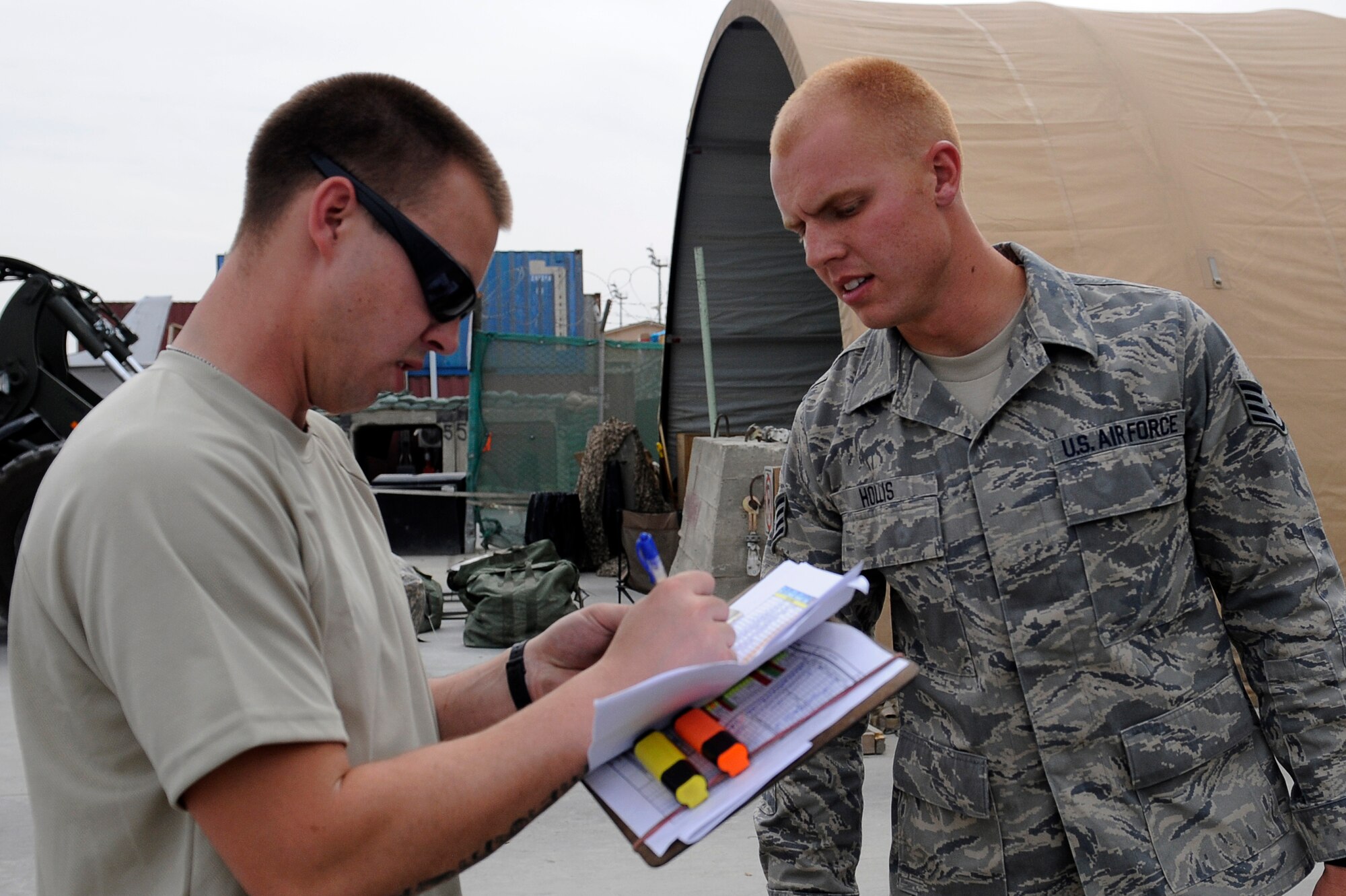 U.S. Air Force Airman 1st Class Brandon Ziegler (left), 455th Expeditionary Aerial Port Squadron, checks Staff Sgt. Hollis?s, name against the manifest at Bagram Airfield, Afghanistan, April 14, 2010. Airman Ziegler is deployed from Travis Air Force Base, Calif., and is from Val Dosta, Ga. (U.S. Air Force photo by/ Tech. Sgt. Jeromy K. Cross/released)