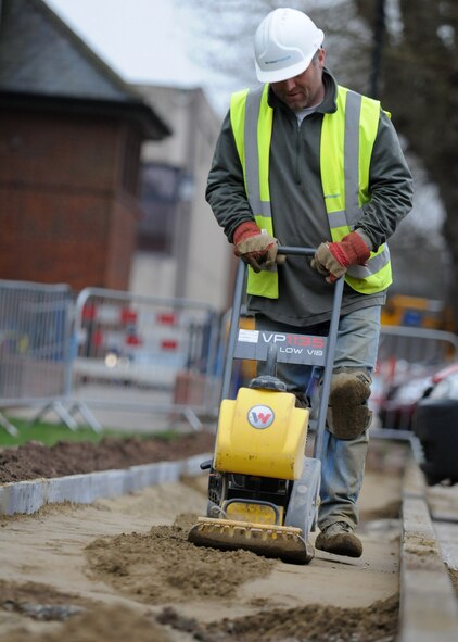 RAF MILDENHALL, England – A Contract worker Paul Wiseman uses a compactor plate to compact and flatten concrete poured into framework during sidewalk construction at the Galaxy Club parking lot April 14. (U.S. Air Force photo/ Staff Sgt. Jerry Fleshman)