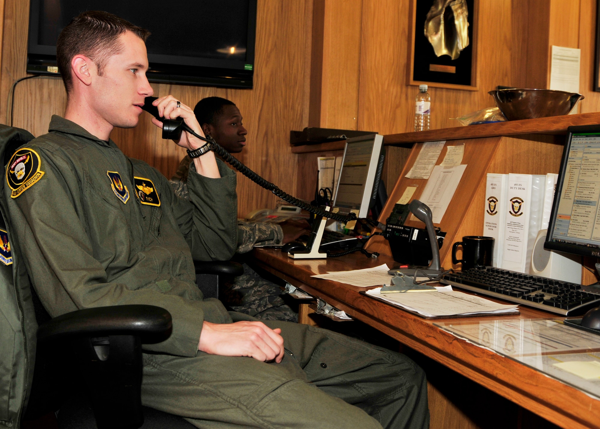 Capt. Mike Conrad, 493rd Fighter Squadron Operations Desk supervisor, answers the phone as Senior Airman Patrick Moton, Aviation Resource Management System manager, inputs data at the 493rd FS Operations Desk on March 26, 2010. (U.S. Air Force photo/Airman 1st Class Tiffany M. Deuel)