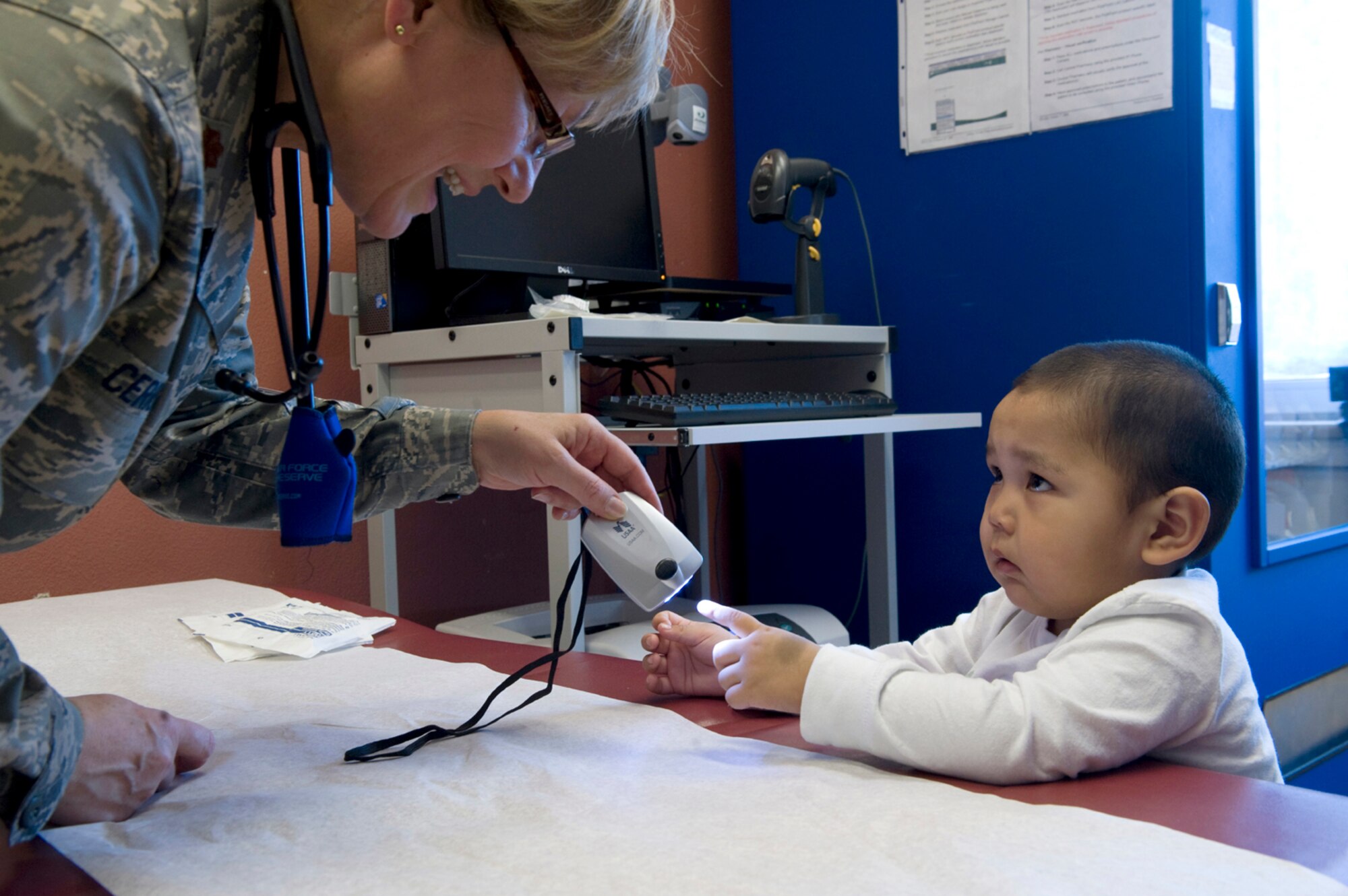 Maj. Emily Cerreta uses a blinking light to gain acceptance from 23-month-old Hikerr Snyder prior to his well-baby checkup April 14, 2010, in Noorvik, Alaska. Major Cerreta is a family nurse practitioner from the 433rd Airlift Wing at Lackland Air Force Base, Texas, and is in Alaska for Operation Arctic Care, a joint medical training exercise.  (U.S. Air Force photo/Master Sgt. Jack Braden)