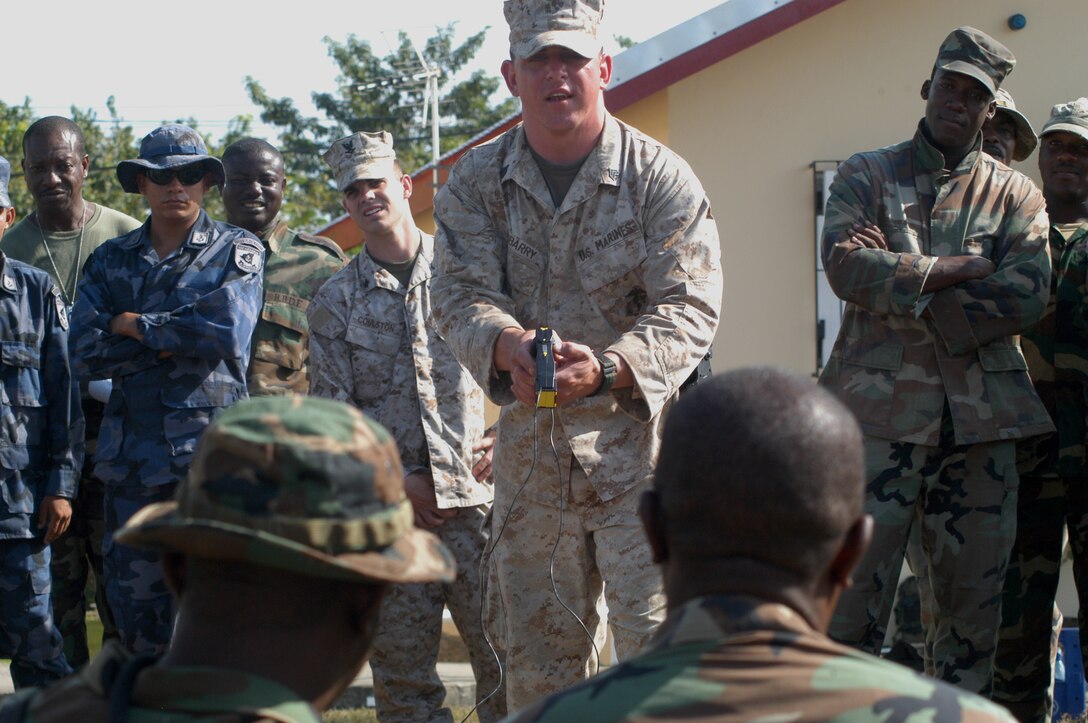 Marine Sgt. John Dubarry, a military policeman with Military Police Co. A, from Lexington, Ky., prepares to deliver a jolt with an X26E taser gun to two Grenadian soldiers. The training was part of a week-long non-lethal weapons course as part of Tradewinds 2010. Tradewinds is a Chairman of the Joint Chiefs directed, U.S. Southern Command sponsored annual exercise that is conducted with Caribbean Basin Partner Nations, designed to improve cooperation in responding to regional security threats.