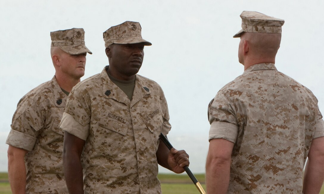 (From left to right) Sergeants Major Scott M. Smith and James Roberts Jr., the incoming and outgoing sergeants major for Headquarters and Service Battalion, U.S. Marine Corps Forces, Pacific, respectively, report to Col. Alan L. Thoma, H&S Bn. commander, during a post and relief ceremony April 16 at Bordelon Field, Camp H. M. Smith, Hawaii. The noncommissioned officer's sword Roberts holds symbolizes his position as the unit's senior enlisted advisor and was ceremoniously passed to Smith during the ceremony.