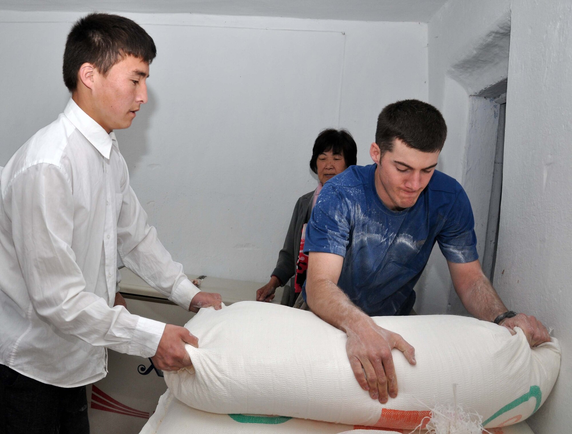 U.S. Air Force Staff Sgt. Kevin Goodlett and students at the Panfilovskaya Boarding School/Orphanage, Kyrgyzstan, unload 100-pound bags of flour donated by the Airmen of the Transit Center April 16, 2010. Sergeant Goodlett is a Louisiana Air National Guardsman deployed to the 376th Expeditionary Security Forces Squadron. (U.S. Air Force photo/Staff Sgt. Carolyn Viss)