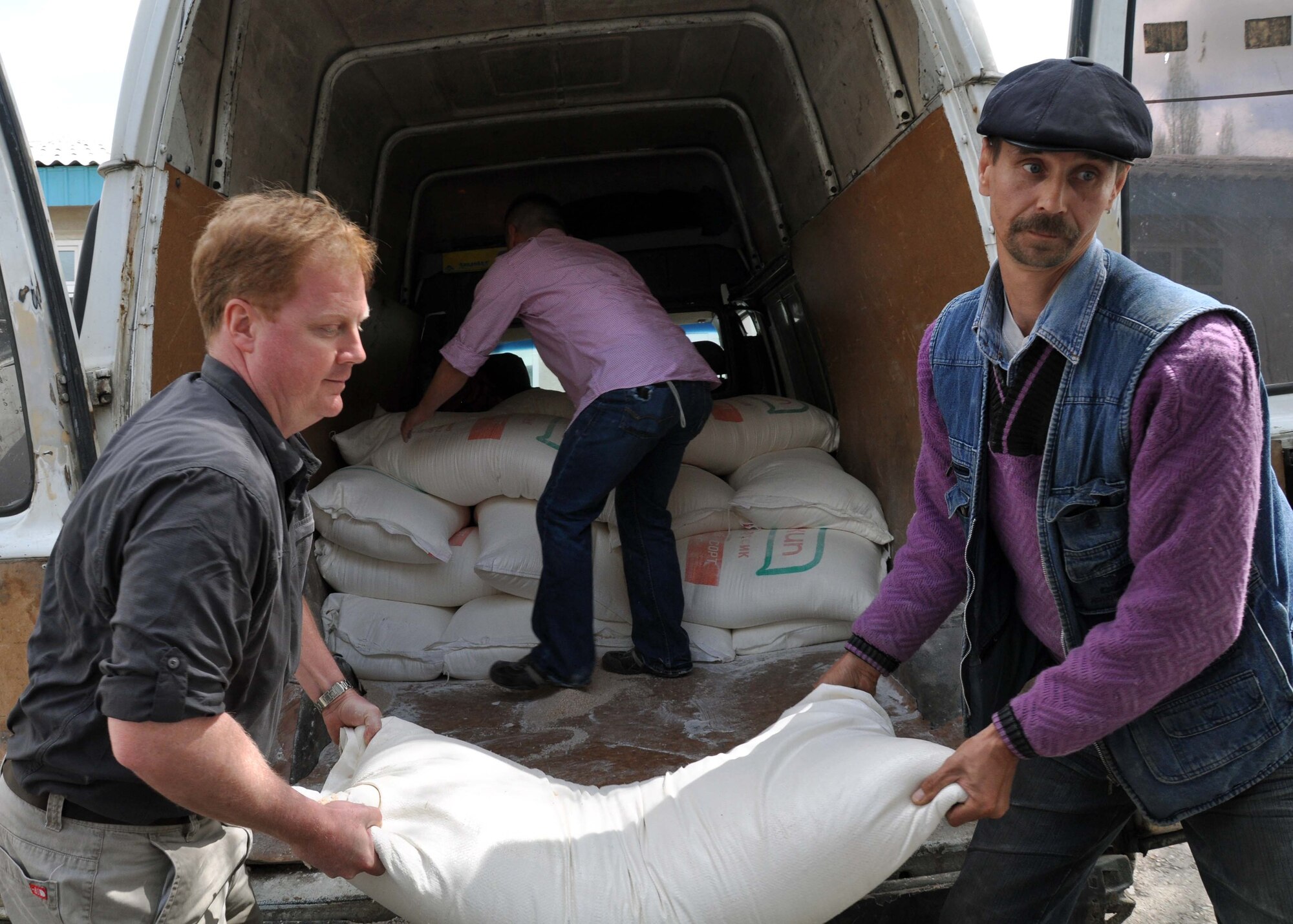 U.S. Air Force Lt. Col. Neal Linch, the Transit Center at Manas humanitarian assistance director, and a staff member of the Panfilovskaya Boarding School/Orphanage, Kyrgyzstan, unload 100-pound bags of flour donated by the Airmen of the Transit Center April 16, 2010. (U.S. Air Force photo/Staff Sgt. Carolyn Viss)