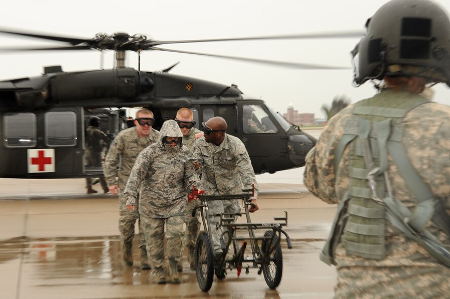 Team McConnell Airmen wheel a North Atlantic Treaty Organization gurney under the direction of Army Sgt. Beth Ramsey, Company C, 2-135th General Support Aviation Battalion UH-60Q Black Hawk helicopter crew chief, during a joint exercise which focused on critical orientation training with a UH-60Q Black Hawk helicopter medical evacuation procedures, including patient loading and unloading April 16, 2010, McConnell Air Force Base, Kan. The 22nd Medical Group, 22nd Security Force Squadron, 22nd Civil Engineer Squadron Fire Department, 22nd CES Explosive Ordnance Disposal and Air Force Reserve 931st Aerospace Medicine Flight conducted a medical evacuation exercise with three UH-60Q Black Hawk Medevac Helos from the Nebraska Army National Guard. (U.S. Air Force photo/Tech. Sgt. Chyrece Campbell)
