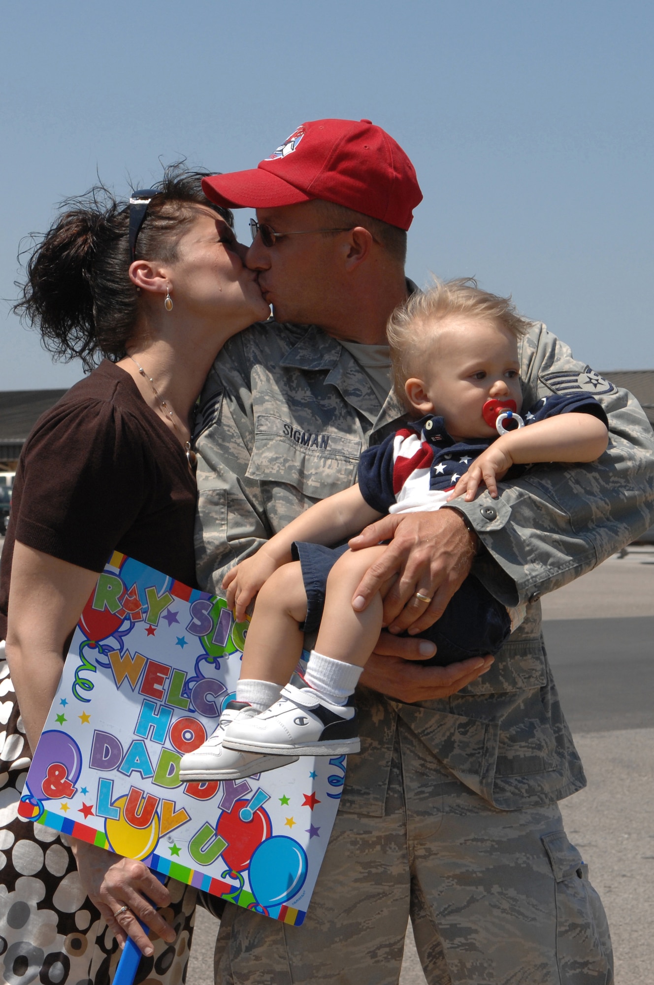 U.S. Air Force Staff Sgt. Ray Sigman, 823rd RED HORSE Squadron, kisses his wife Robyn while holding his son Alexander during a homecoming ceremony April 15, 2010, Hurlburt Field, Fla. RED HORSE returned home from a six-month deployment to Southwest Asia. (DoD photo by U.S. Air Force Master Sgt. Scott MacKay)(RELEASED)