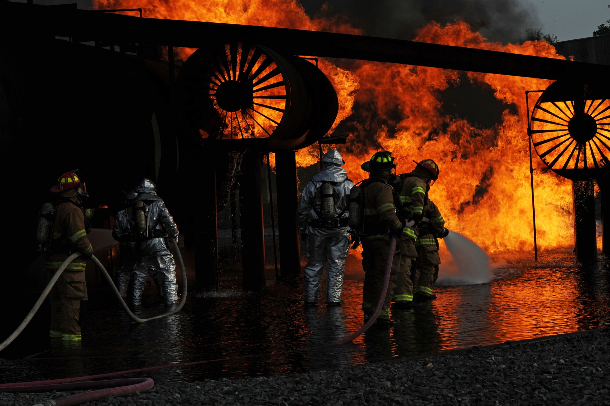 BARKSDALE AIR FORCE BASE, La. – Shreveport firefighters move in to extinguish a fire during their annual joint - live fire training here April 7. Firefighters wear proximity firefighting gear since there is no training gear for this purpose. The special aluminized cover and barrier help reflect some heat away from the firefighters while the self – contained breathing apparatus allows them to breathe clean air for approximately 40 minutes in working conditions. The proper wear is imperative to their safety and survival, since the entry into the training aircraft exposes them to temperatures reaching 2,000 degrees Fahrenheit. (U.S. Air Force photo by Senior Airman La’Shanette V. Garrett)(RELEASED)