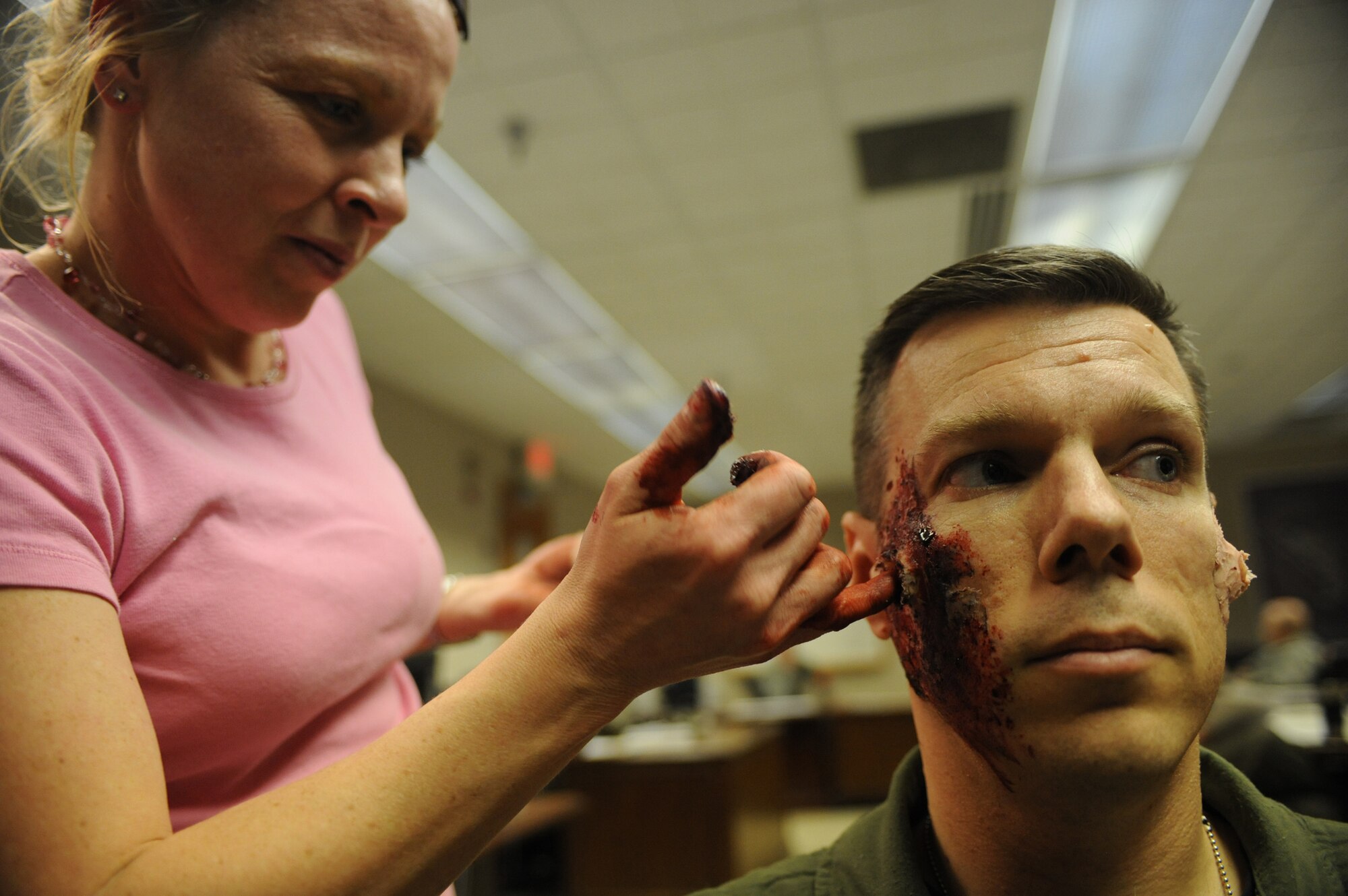 (Left) Tech. Sgt. Tricia Carnes, 28th Medical Squadron NCO in-charge of medical readiness, applies moulage to Maj. Brian Ignotowicz, 28th Bomb Wing chief of wing plans division, April 15. The moulage is used to give a real world look to a simulated injury during the “active shooter” exercise, which tested the total reaction and response time of the 28 BW. (U.S. Air Force photo/Senior Airman Adam Grant)       