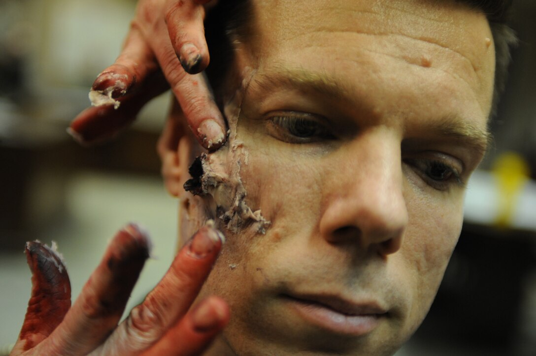 Maj. Brian Ignotowicz, 28th Bomb Wing chief of wing plans division, sits as a latex spread is placed on his face during the “active shooter” exercise, April 15. The latex spread is used to simulate a bullet entrance wound. Once the simulated wound is applied the next step is to add the “blood,” which is made from corn starch. (U.S. Air Force photo/Senior Airman Adam Grant)   