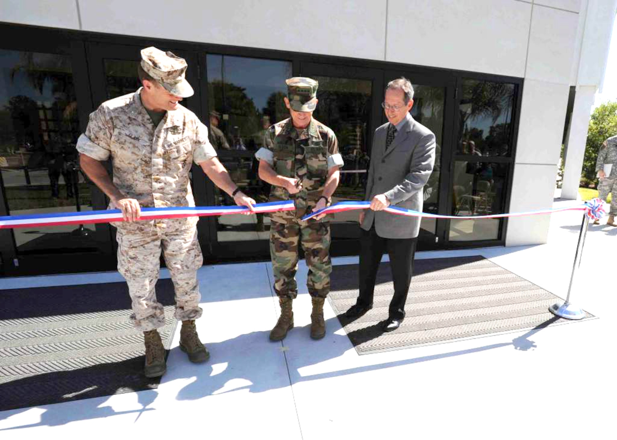 Adm. Eric T. Olson, commander of U.S. Special Operations Command, cuts the ribbon for Dagger Hall and Commando Center as Acquisition and Senior Procurement Executive Mr. James Cluck, (right), and Director of Operations Brig. Gen. Mark Clark (left), look on during the opening ceremony of both buildings Monday. Dagger Hall, Building 501D, is 96,000 square feet and will house the operations and intelligence directorates. Commando Center will serve the Special Operations Research, Development, & Acquisition Center with its five program executive offices, the Special Operations Forces Integration Laboratory, and the Science and Technology Directorate.