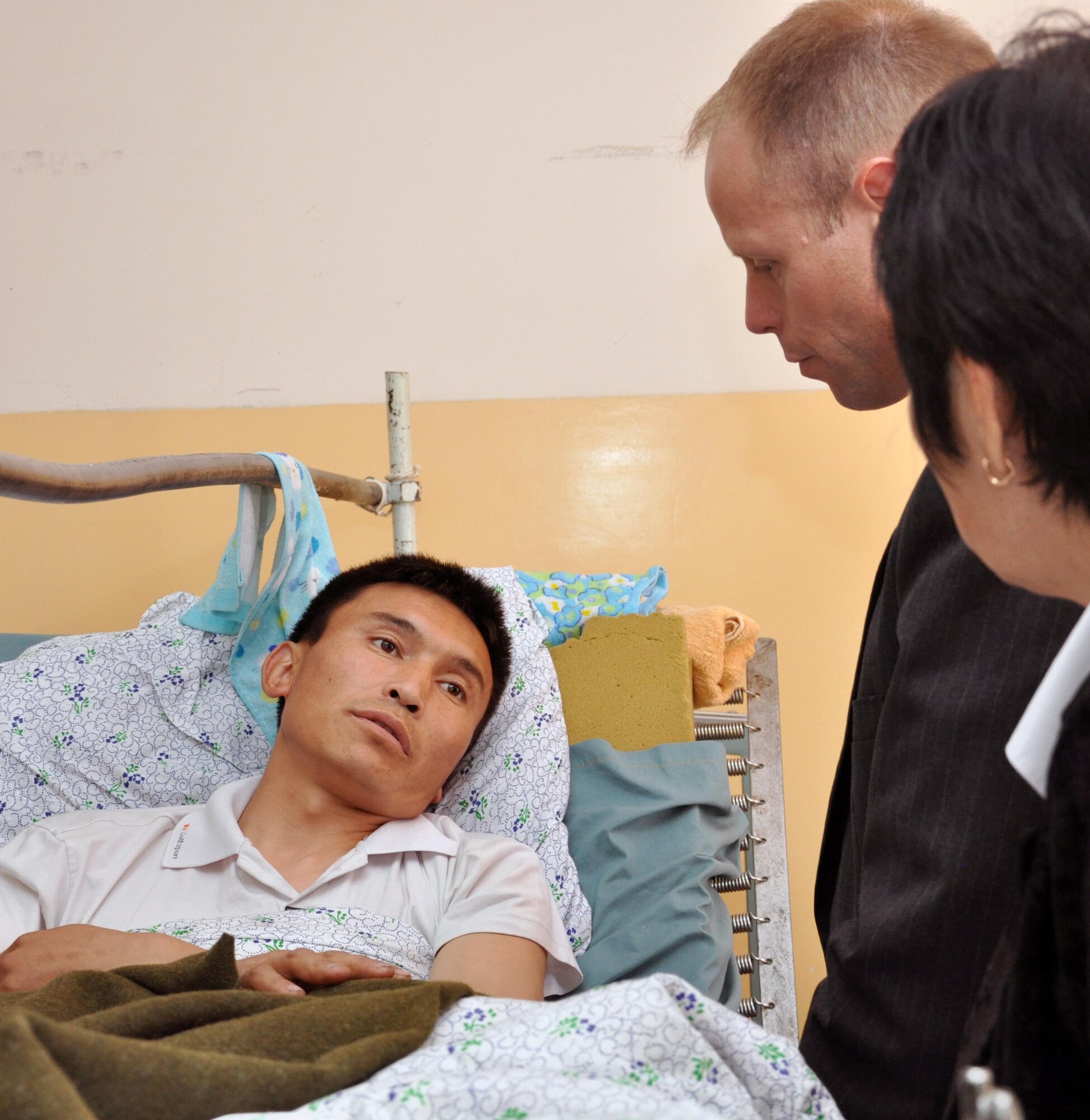 Col. Blaine Holt, director of the Transit Center at Manas, Kyrgyzstan, left, speaks to a hospitalized patient who was wounded in last week?s unrest, at the Center for Traumatology in Bishkek, Kyrgyzstan, April 15, 2010. He gave the wounded people tee shirts on behalf of the Airmen at the Transit Center, after donating needed food and medical supplies to the hospital. (U.S. Air Force photo/Staff Sgt. Carolyn Viss)