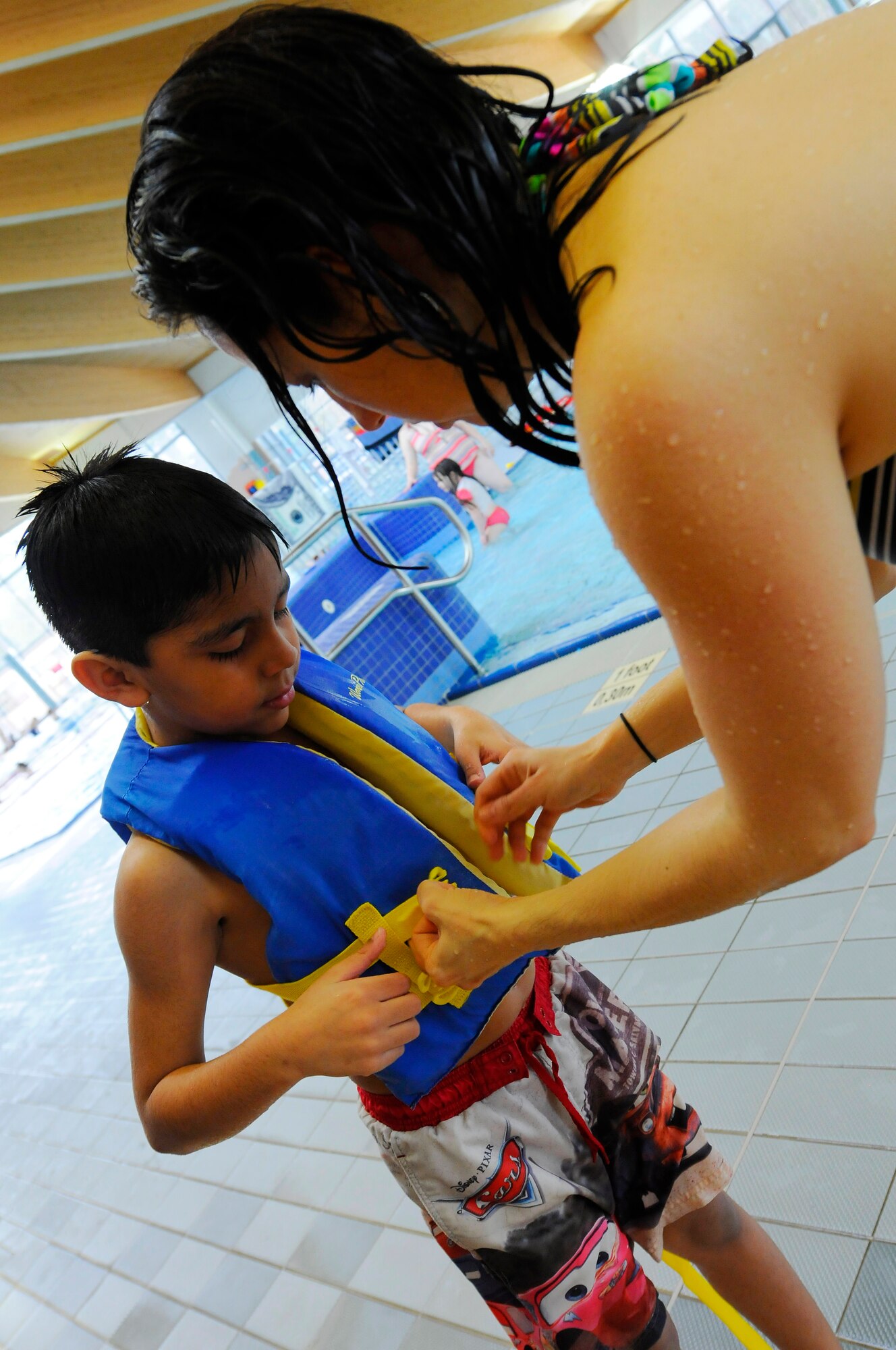 April Moyer helps 9-year-old, Brian Gaticia, put on a life jacket at the Aquatic Center, Ramstein Air Base, Germany, April 16, 2010. Vogelweh Youth Center hosted the Vogelweh Spring Break Camps during a week-long series of events for children ages 9-12 in the Kaiserslautern Military Community, consisting of Sports, Outdoor Adventure, The Arts  and Swimming Camps ending with a movie day. This event is one of many events supporting the Month of the Military Child. (U.S. Air Force photo by Airman 1st Class Brea Miller)