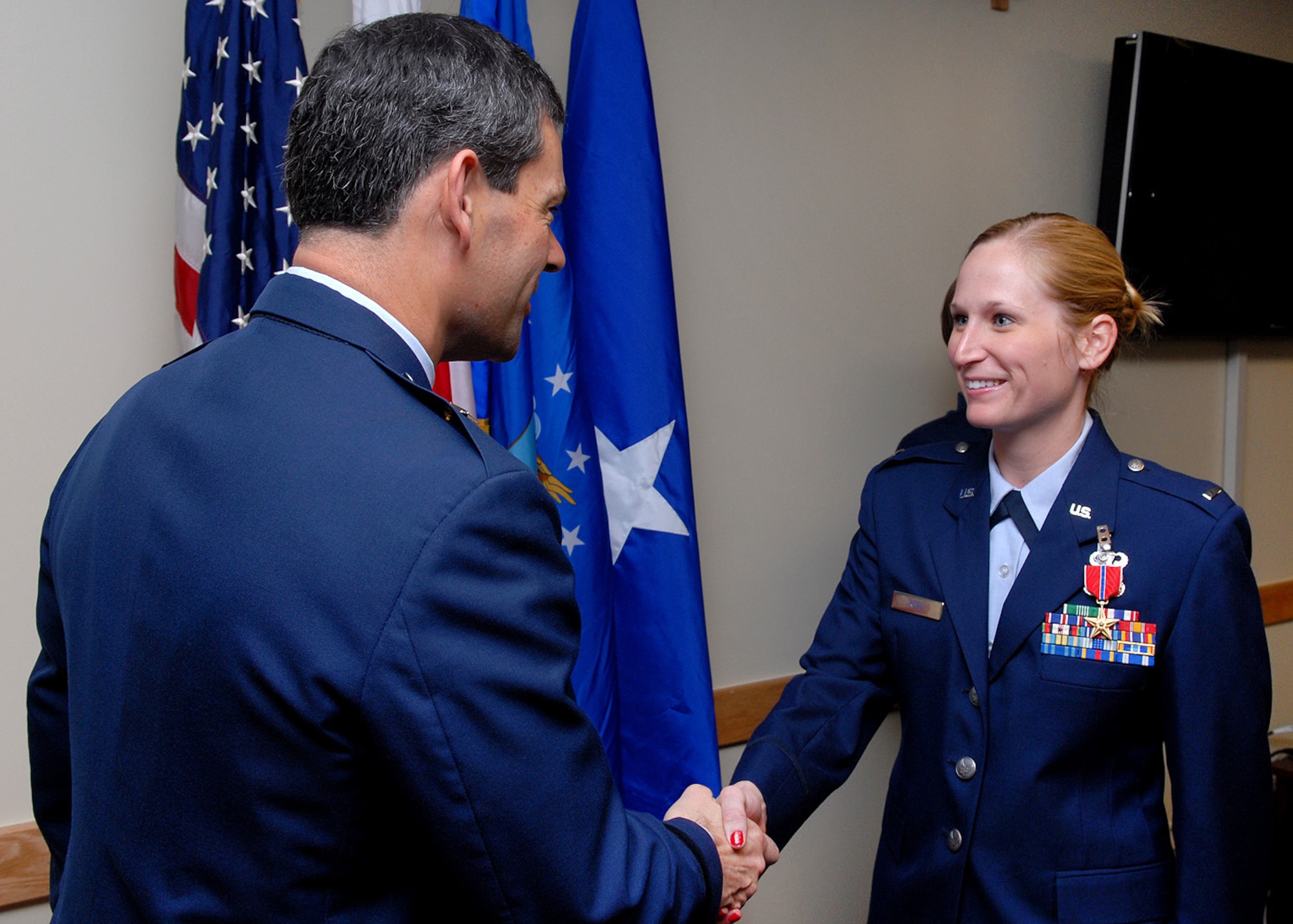 First Lt. Amanda Reed (left), 18th Aircraft Maintenance Squadron, is congratulated by Brig. Gen. Ken Wilsbach, 18th Wing commander, after being awarded the Bronze Star medal April 16 for her actions in Afghanistan as a battle captain with the Army last year. The lieutenant led a joint team of Airmen, soldiers and sailors who trained Afghan National Army troops under Combined Security Transition Command - Afghanistan. (Air Force/Junko Kinjo)