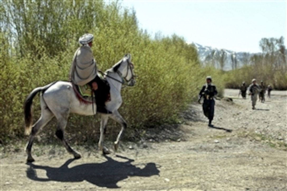 An Afghan man rides through a dry river bed and meets a patrol led by U.S. Army paratroopers and Afghan national police near the village of Bakshikhala in Kherwar district, Logar province, Afghanistan, April 12, 2010. The paratroopers are assigned to Company C, 1st Squadron, 91st Infantry Regiment, 173rd Airborne Brigade Combat Team.