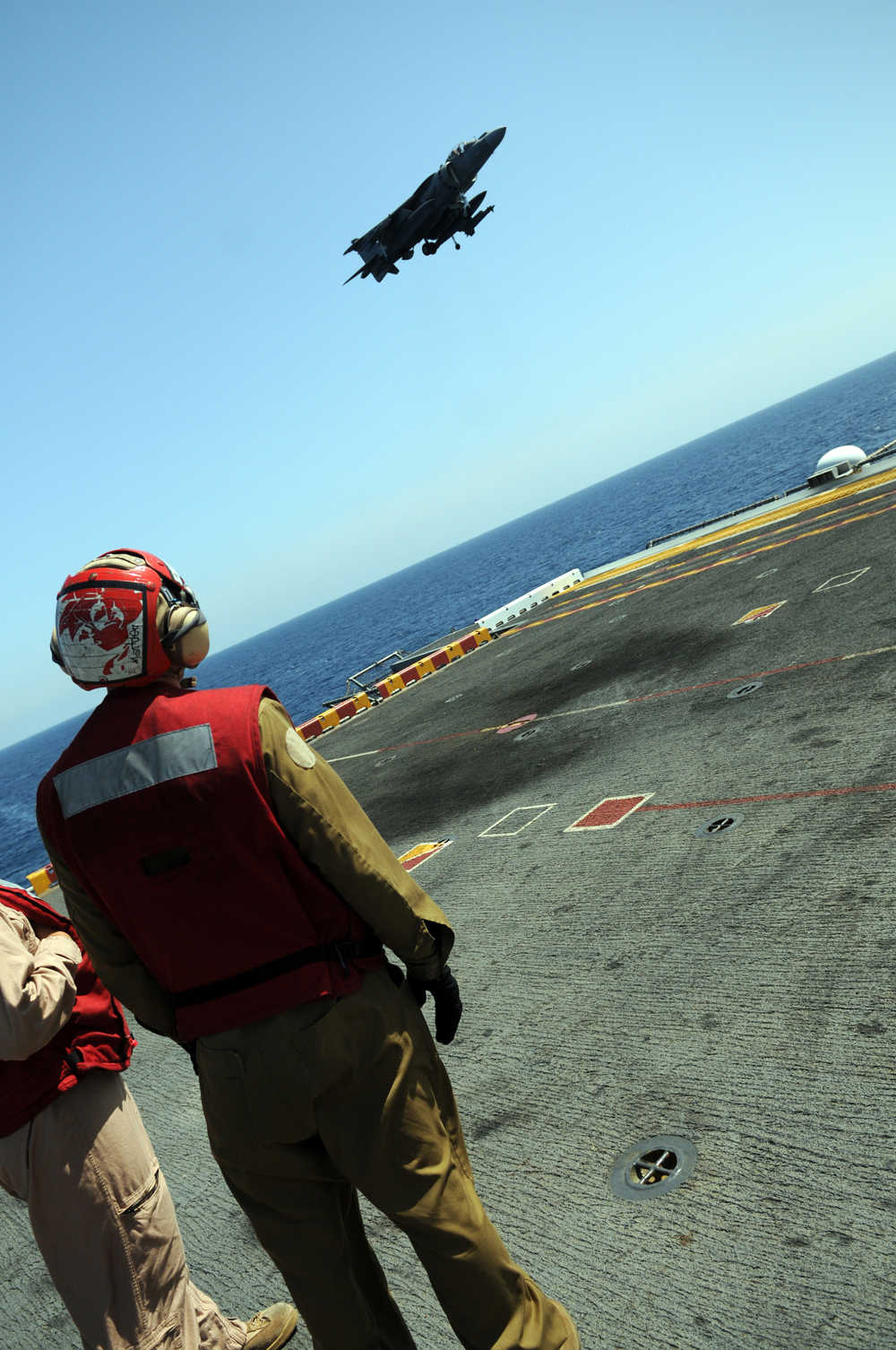 Gunnery Sgt. Mike Madden, right, Marine Attack Squadron 311 detachment staff noncommissioned officer in charge, and Sgt. Joseph Aranda, squadron ordnance NCOIC, watch Capt. Michael Cassidy, squadron pilot, land on the flight deck of the USS Peleliu after flying from the Marine Corps Air Station in Yuma, Ariz., April 16, 2010. Six AV-8B Harriers and approximately 80 squadron Marines left Yuma April 15 to participate in their third and final predeployment training evolution off the coast of California. The exercise, which began April 16 and is scheduled to end April 27, included the entire 15th Marine Expeditionary Unit. The squadron is slated to deploy to the Pacific and Indian Oceans with the 15th MEU in May. The remainder of the squadron deployed to Japan aboard the USS Essex with the 31st MEU in January. The last time the squadron deployed with the 15th MEU was in 2008.