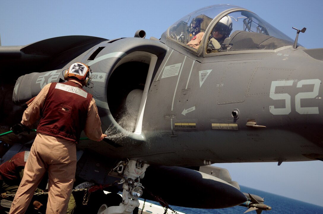 Sgt. Nathan Thul, Marine Attack Squadron 311 powerline mechanic, sprays down the engine intake of an AV-8B Harrier as its pilot, Capt. Michael Lippert, prepares to exit the aircraft after flying it onto the USS Peleliu from the Marine Corps Air Station in Yuma, Ariz., April 16, 2010. Six AV-8B Harriers and approximately 80 squadron Marines left Yuma April 15 to participate in their third and final predeployment training evolution off the coast of California. The exercise, which began April 16 and is scheduled to end April 27, included the entire 15th Marine Expeditionary Unit. The squadron is slated to deploy to the Pacific and Indian Oceans with the 15th MEU in May. The remainder of the squadron deployed to Japan aboard the USS Essex with the 31st MEU in January. The last time the squadron deployed with the 15th MEU was in 2008.