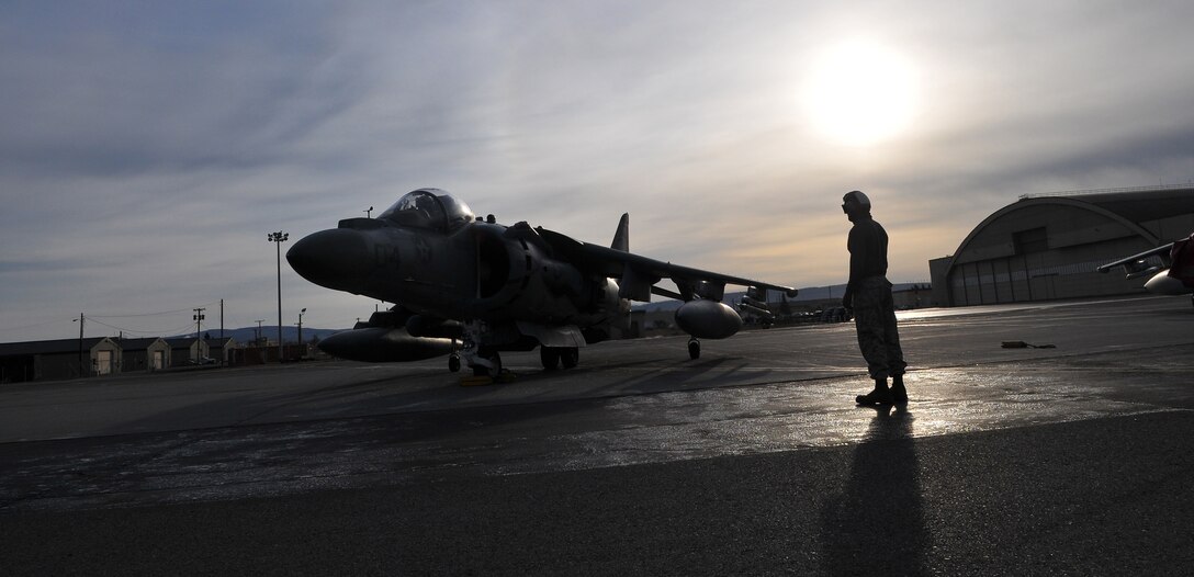 Sgt. Jensen Depue, Marine Attack Squadron 211 powerline mechanic, waits for Capt. Colin Newbold, squadron pilot, to take off in an AV-8B Harrier on the flight line of Eielson Air Force Base, Alaska, April 16, 2010. More than 160 Marines from VMA-211 and Marine Aviation Logistics Squadron 13 flew north to participate in Exercise Red Flag-Alaska, one of the largest joint-service exercises in the U.S. military. The exercise is meant to increase pilots' survivability, running them through combat missions including ordnance delivery, enemy evasion and aerial refueling.