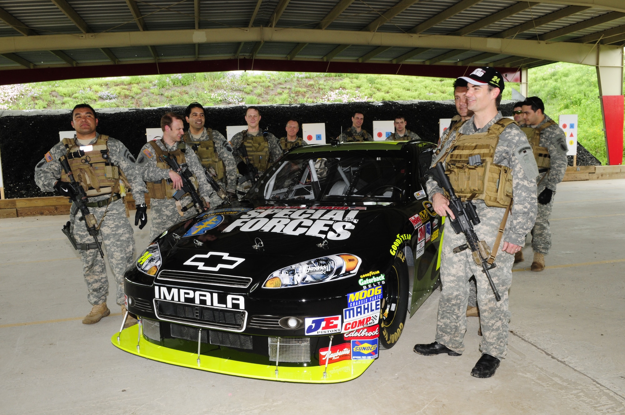 Suited up with Army National Guard equipment and uniform (except for cap and boots), NASCAR driver Jeff Gordon joins National Guard Security Forces Soldiers with his #24 car sporting a new paint scheme and graphics honoring the elite Soldiers, in Texas, on April 15, 2010. (U.S. Air Force photo by Senior Master Sgt. Mike Arellano/Released)