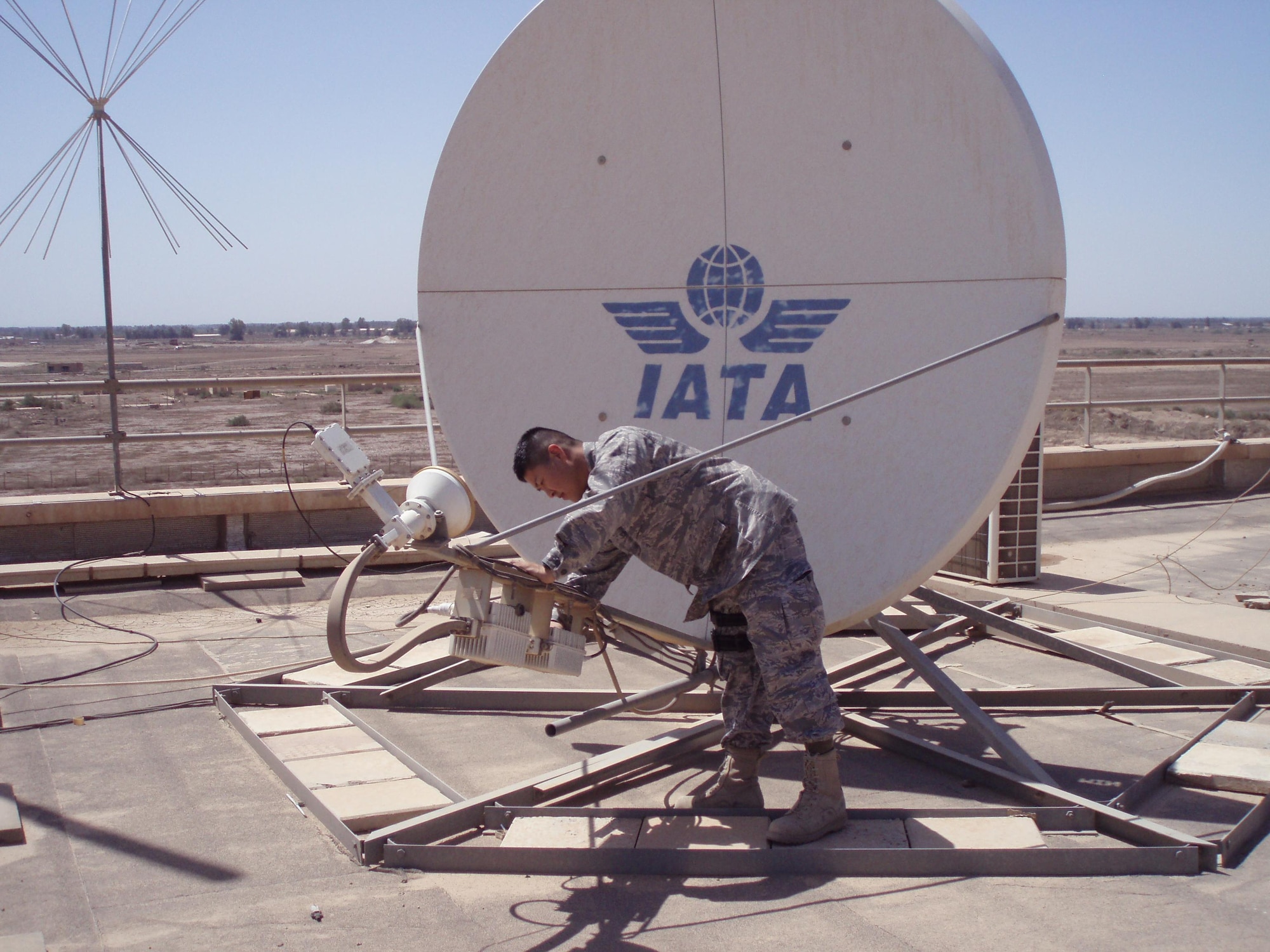 Captain Kurando Mensen inspects a Very Small Aperture Terminal dish at a civilian airport in Iraq. Captain Mensen has advised and assisted the Iraqi Civil Aviation Authority in building an operational VSAT system that allows civilian and commercial air traffic to fly safely in Iraqi. (Courtesy photo)