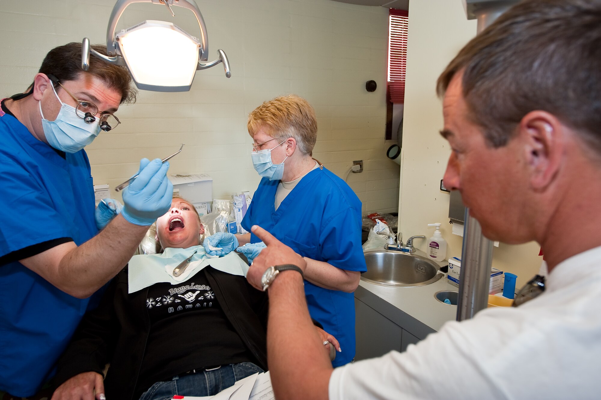 U.S. Air Force Maj. Joshua Wyte, Dentist, 140th Medical Group, Buckley Air Force Base, Colorado Air National Guard, shows a silver point, a small rod used for filling teeth, to Kelly Turzanski and his wife Holly during oral surgery to remove her cracked tooth as Tech. Sgt. Patricia O'Lane, Dental Technician with the 140th Medical Group prepares some gauze for the removed tooth at the Kahuku Medical Center, Hawaii, March 18, 2010. (U.S. Air Force photo/Master Sgt. John Nimmo, Sr.) (RELEASED)
