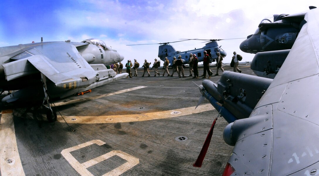 Two Marine Attack Squadron 311 AV-8B Harriers warm up their engines as a line of infantry Marines with the 15th Marine Expeditionary Unit file into a CH-46 helicopter on the flight deck of the USS Peleliu April 18, 2010. Six Harriers and approximately 80 squadron Marines left Yuma April 15 to participate in their third and final predeployment training evolution off the coast of California. The exercise, which began April 16 and is scheduled to end April 27, included the entire 15th MEU. The squadron is slated to deploy to the Pacific and Indian Oceans with the 15th MEU in May. The remainder of the squadron deployed to Japan aboard the USS Essex with the 31st MEU in January. The last time the squadron deployed with the 15th MEU was in 2008.
